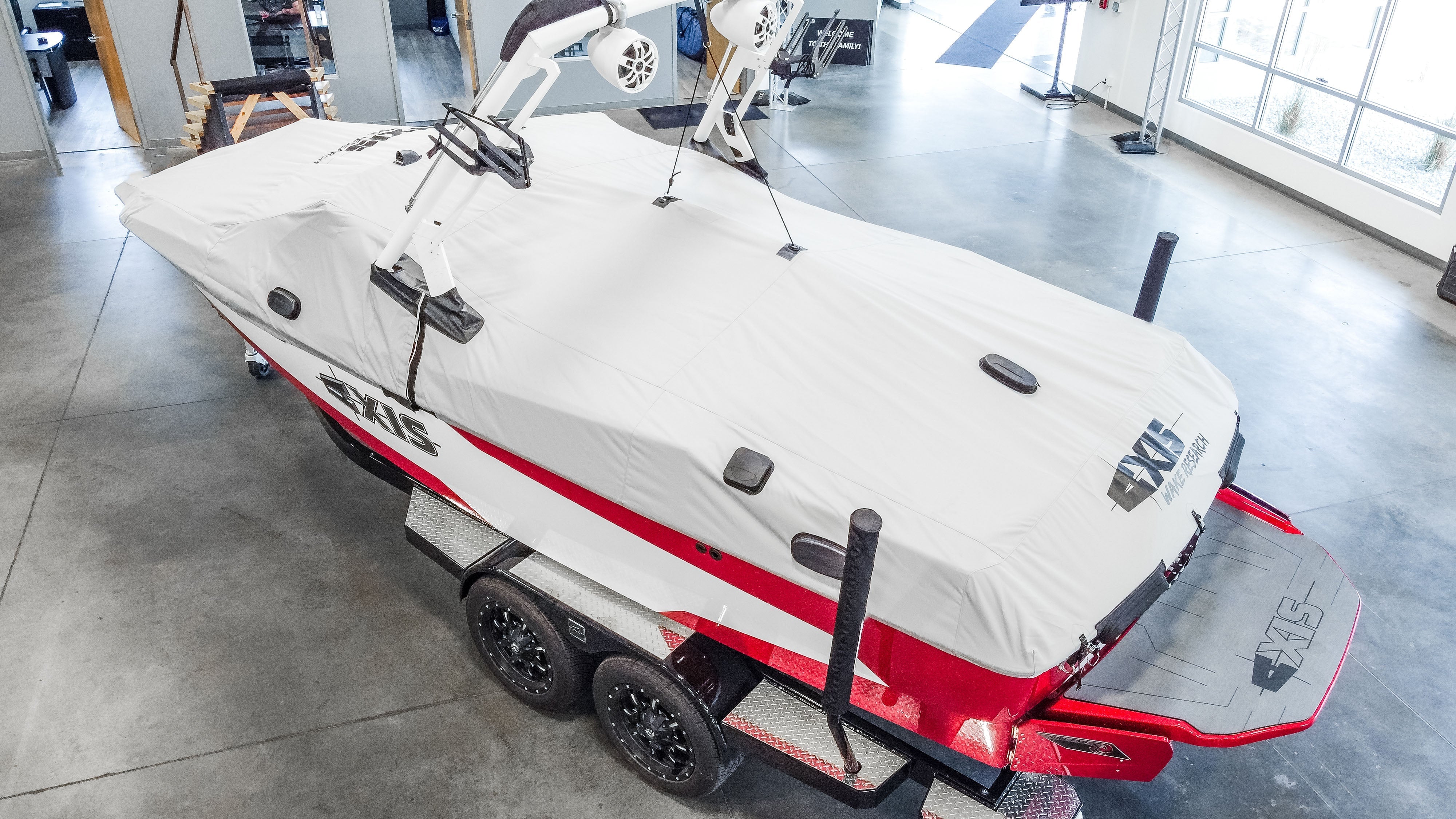 Open box image of a T250 Cover for AW20 Tower with Swim Platform, cover, and taps, mounted on a red and black boat on a trailer.