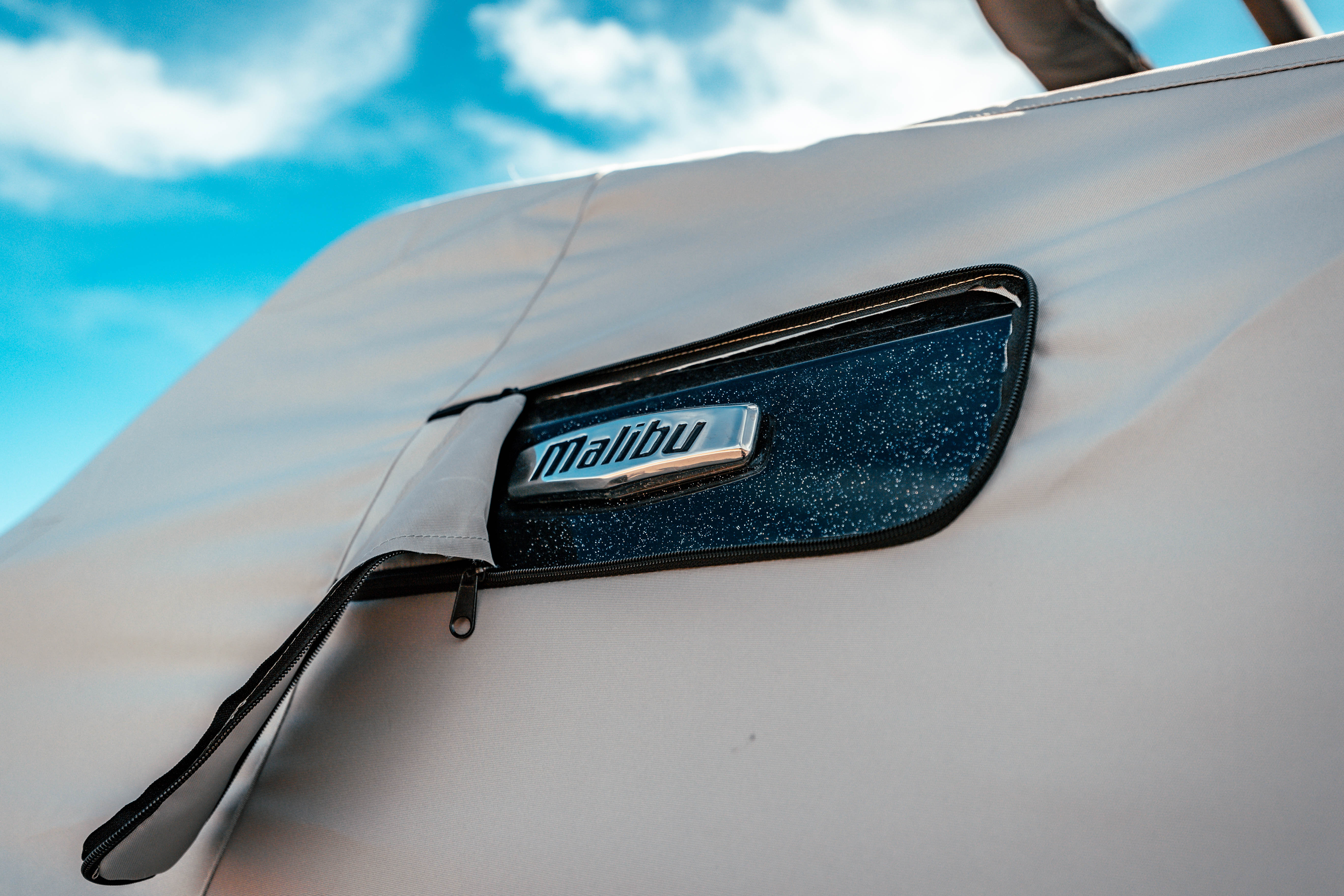 Close-up of a Malibu 26 LSV cover with a GX Tower Down label, featuring a zipper and a textured black and blue Malibu logo.