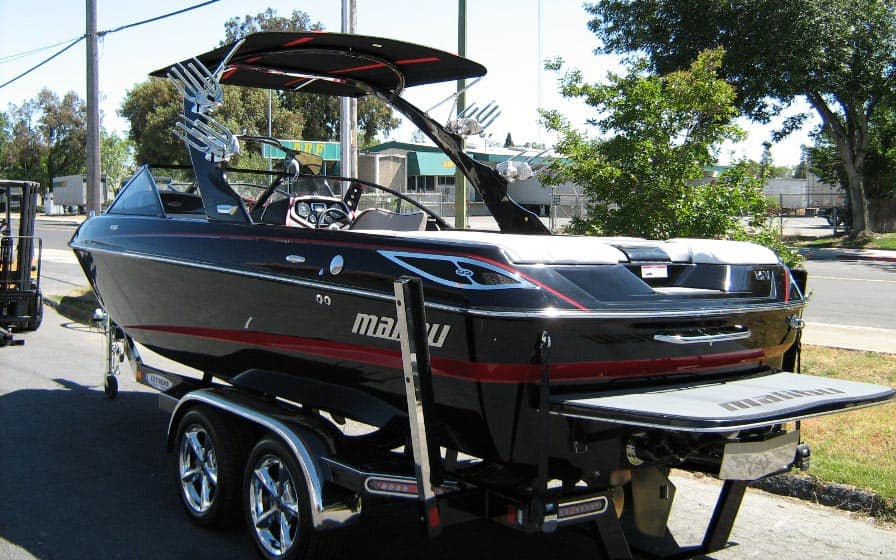 Malibu Illusion XS Bimini top installed on a black boat with trailer, designed for 2008-2009 Malibu boats.