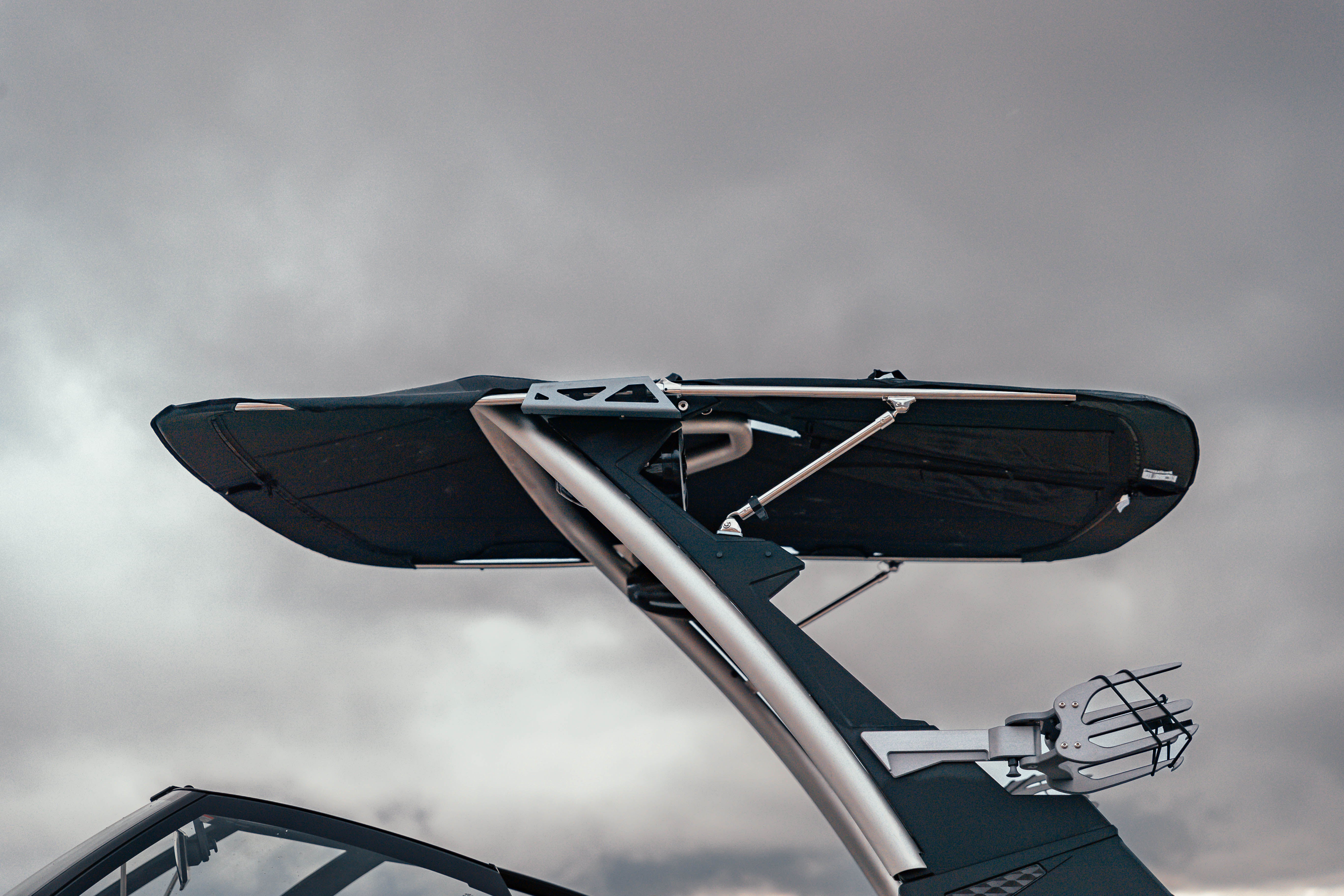 Close-up of Malibu GX Bimini with extension frame mounted on a boat, featuring a black fabric cover and silver support bars.