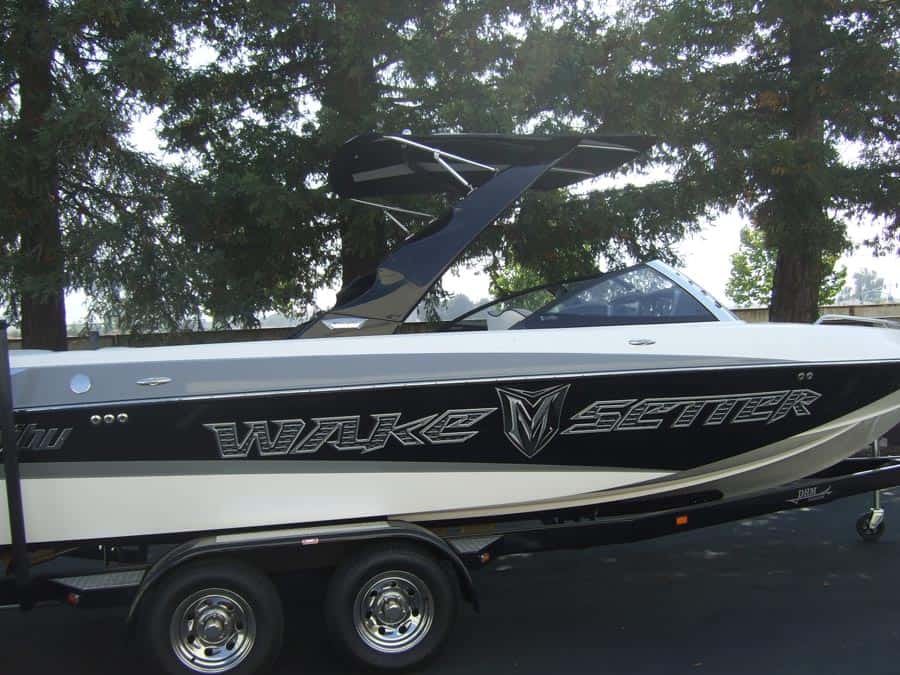 Malibu Illusion XS Bimini top installed on a Wake Setter boat, mounted on a trailer, with trees in the background.