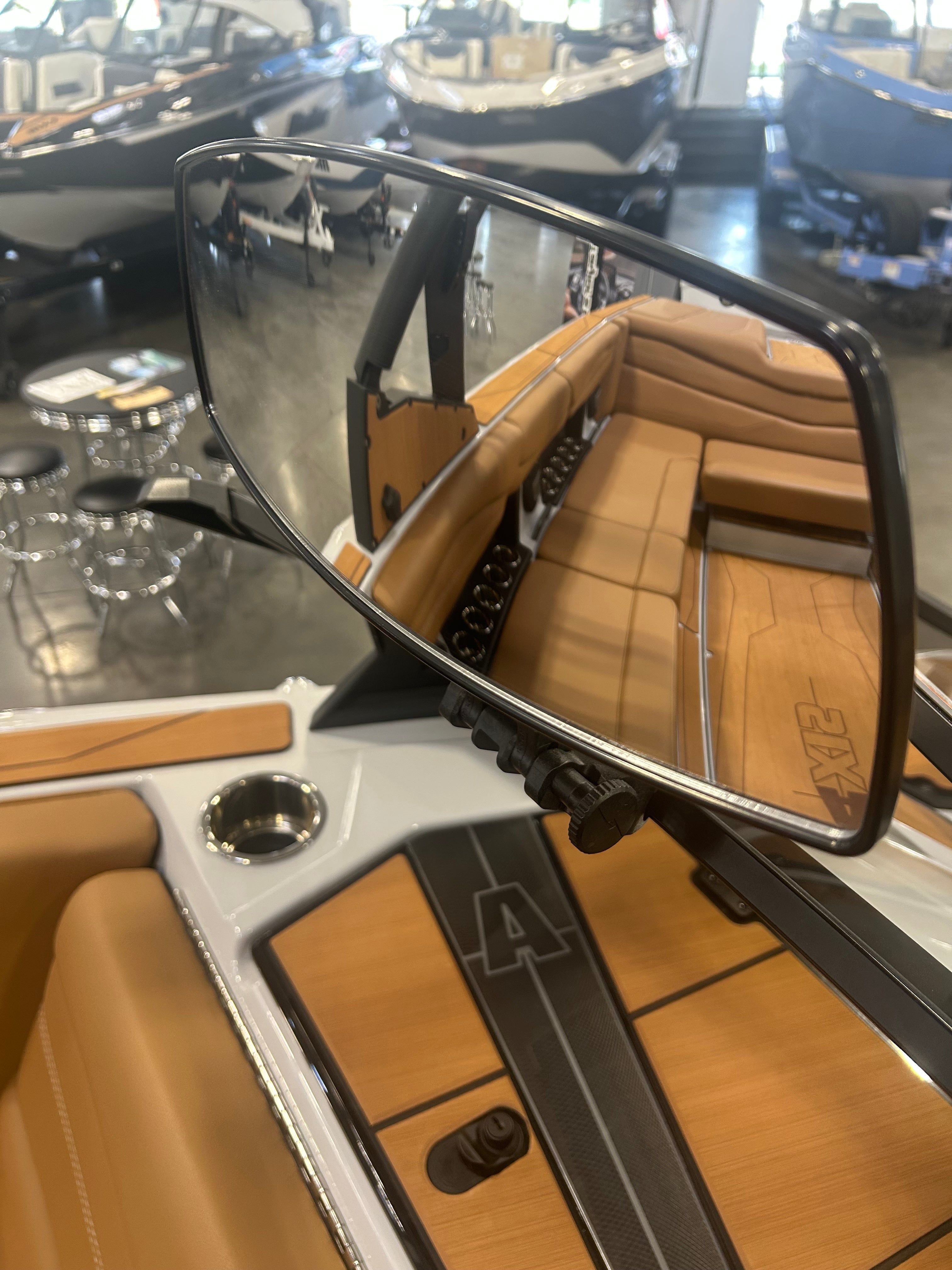 Reflective PTM Pro Mirror showing the boat's interior with tan leather seating and wood accents, in a boat showroom.
