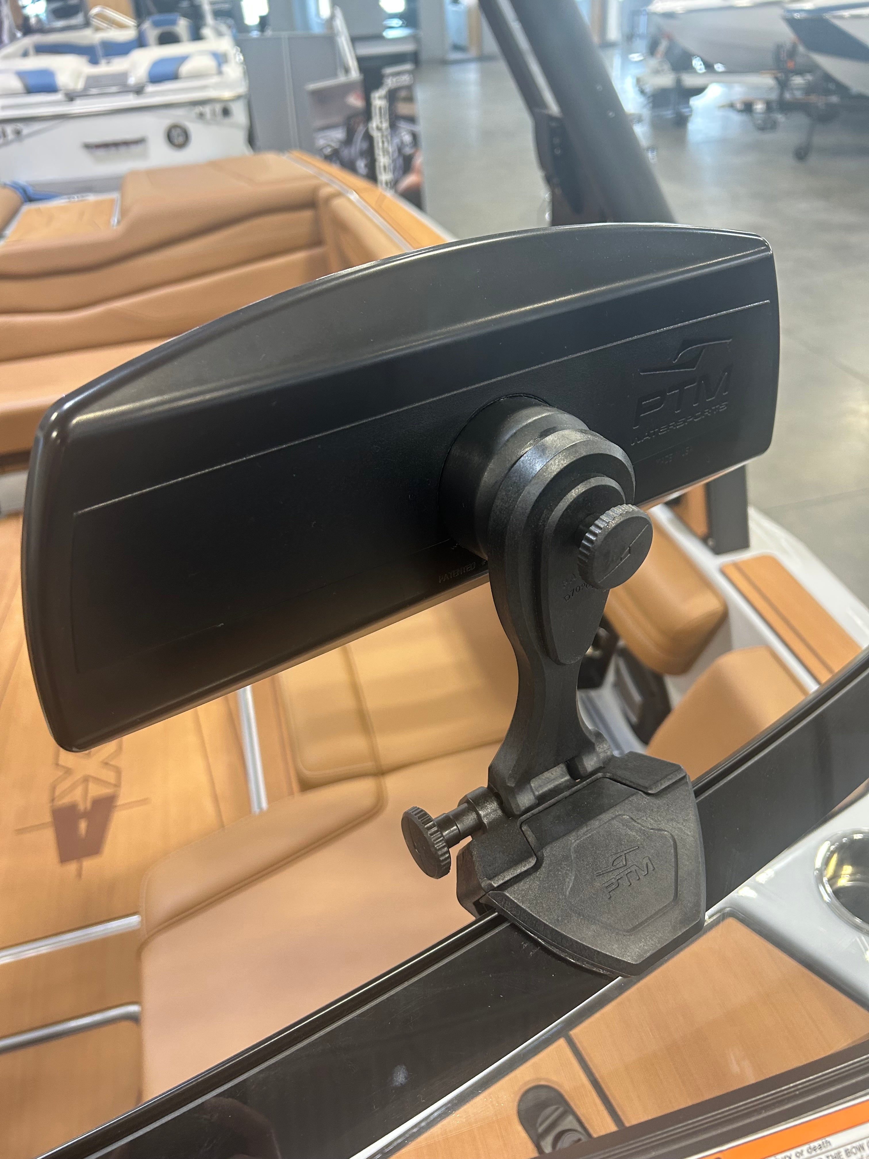 Close-up of a PTM Pro Mirror mounted on a boat, with a tan leather seat and boat accessories in the background.