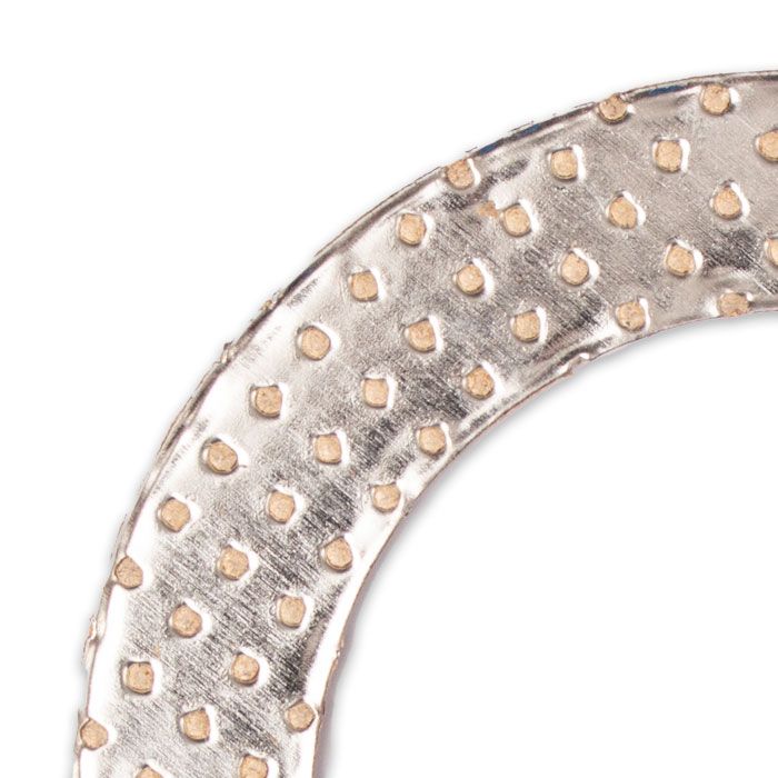 Close-up of a metallic armored exhaust elbow gasket with reinforced dotted pattern for sealing and durability.