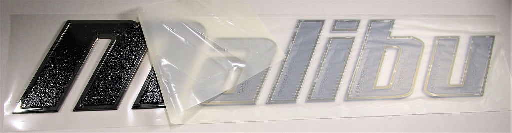 Black Malibu Emblem, 40 inches, with a textured surface and silver outline, partially covered by a clear protective film.