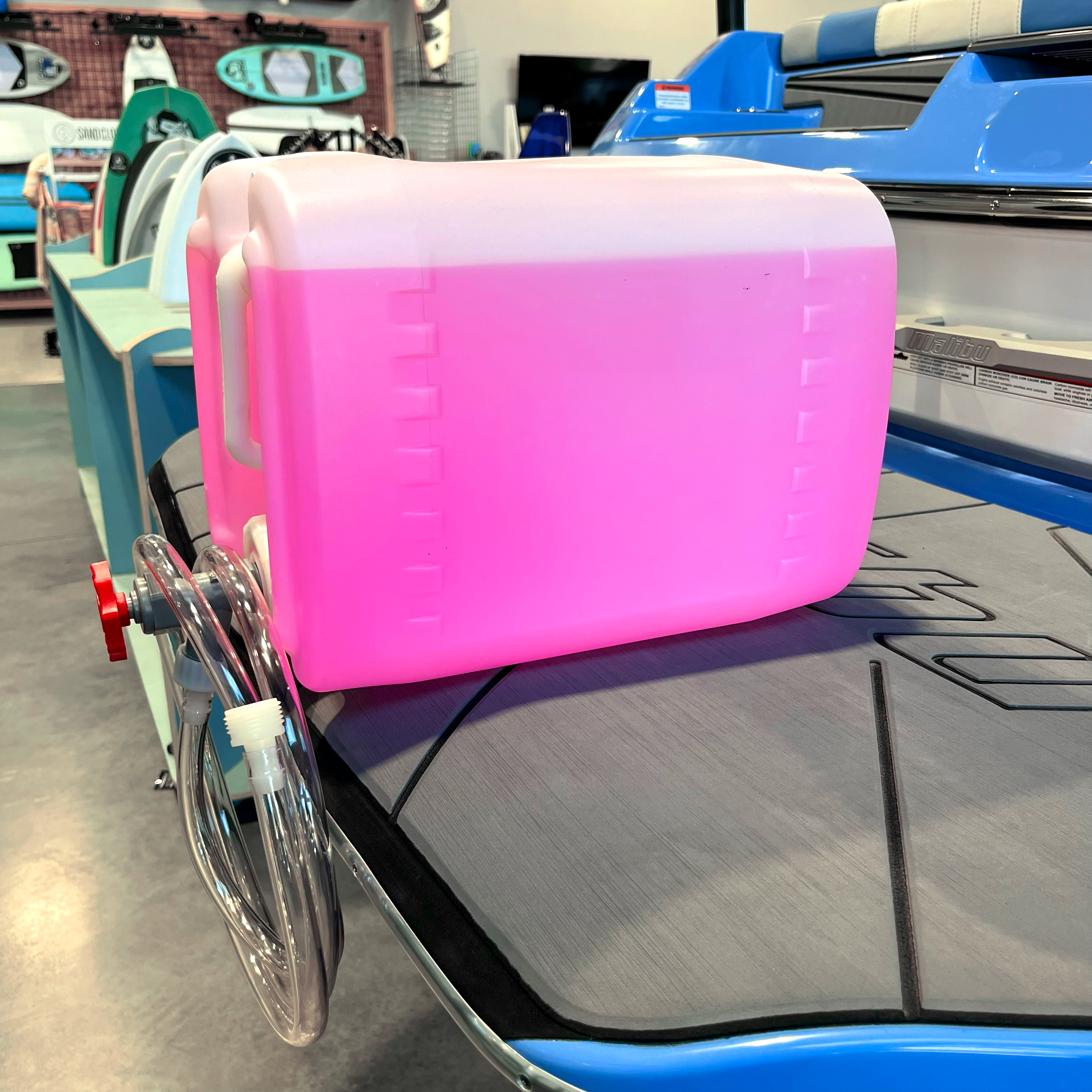 5-gallon winterize jug designed for boat maintenance, featuring a pink liquid and attached hose for easy use.
