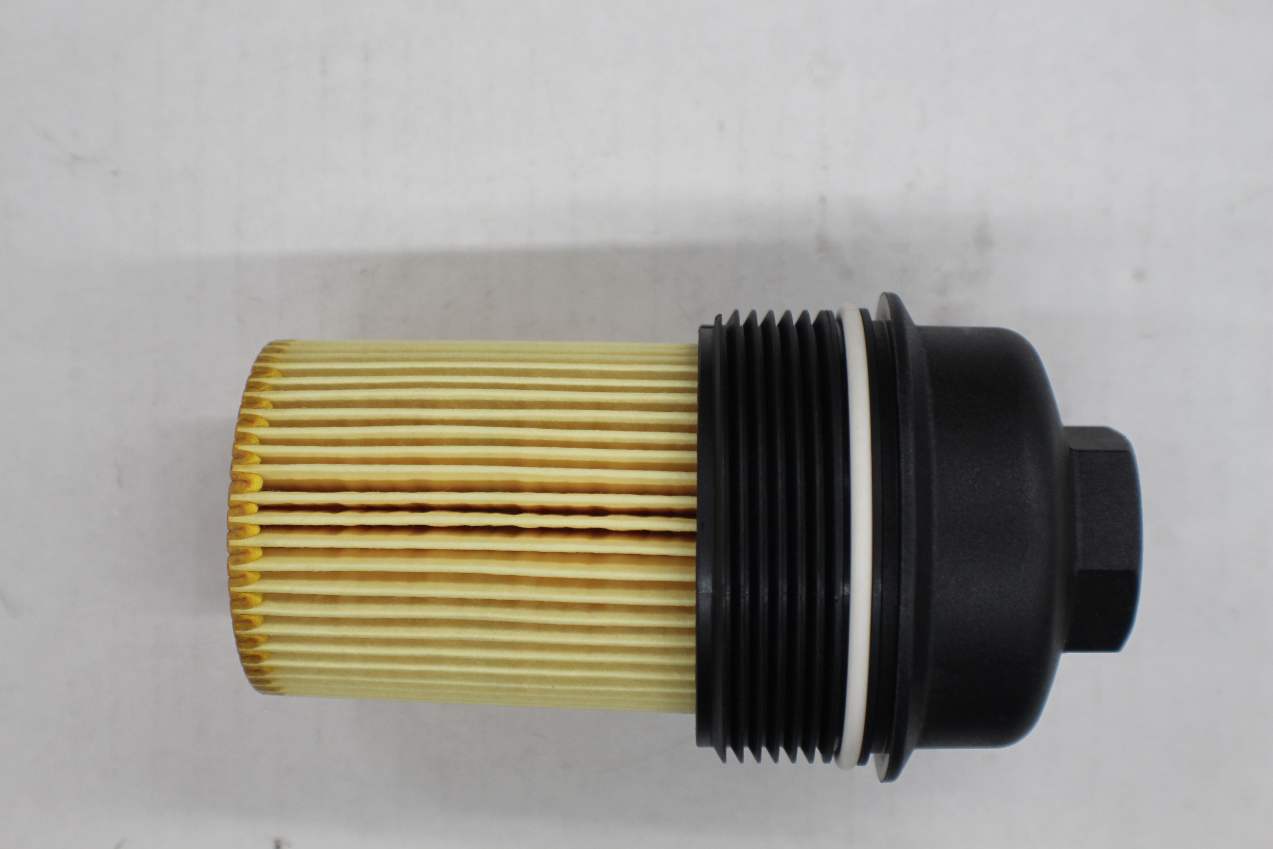 Oil cartridge cap and filter for Ford 6.2L Raptor, featuring a black plastic cap with a white sealing ring and a pleated yellow filter element.