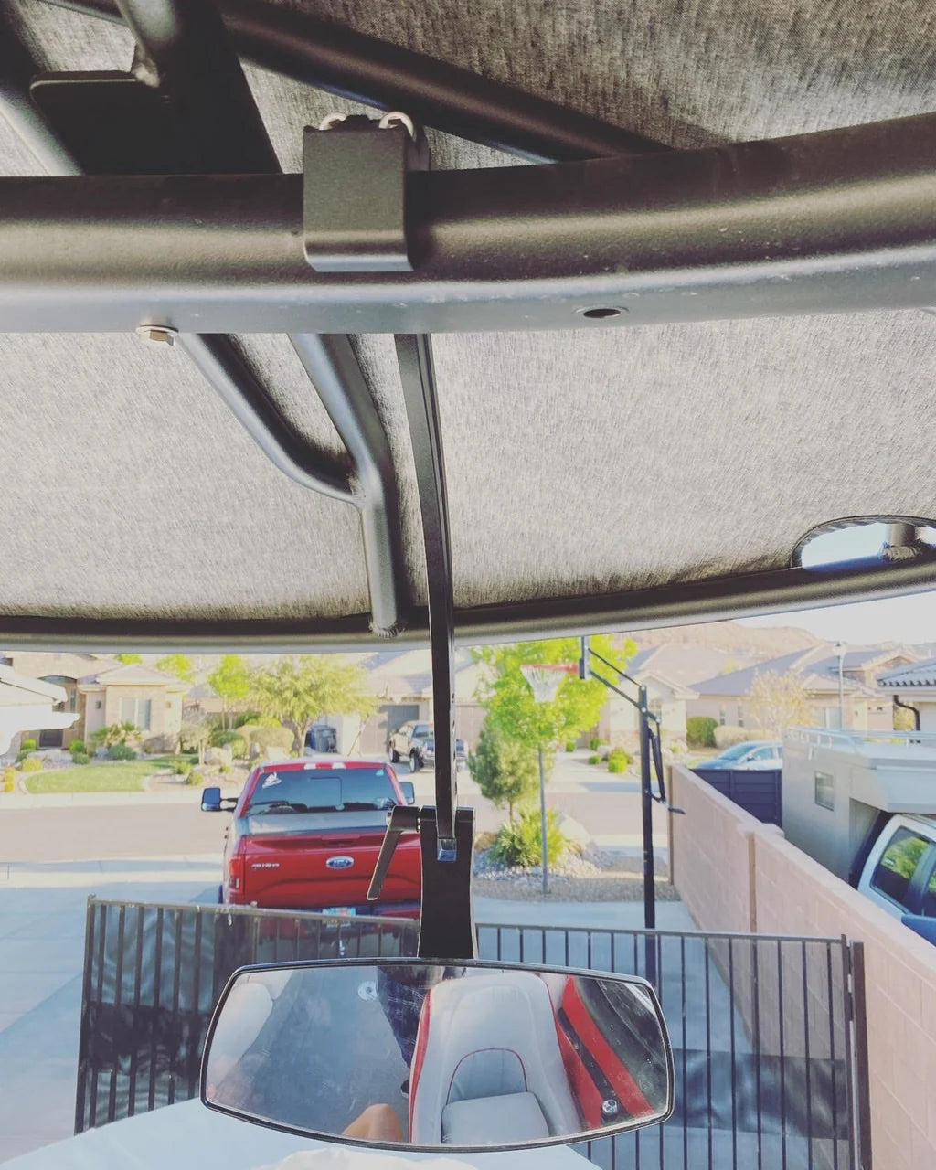 View from underneath a mirror tower arm labeled Illusion X, showing the arm's black metal structure and a rearview mirror reflecting the vehicle's interior.