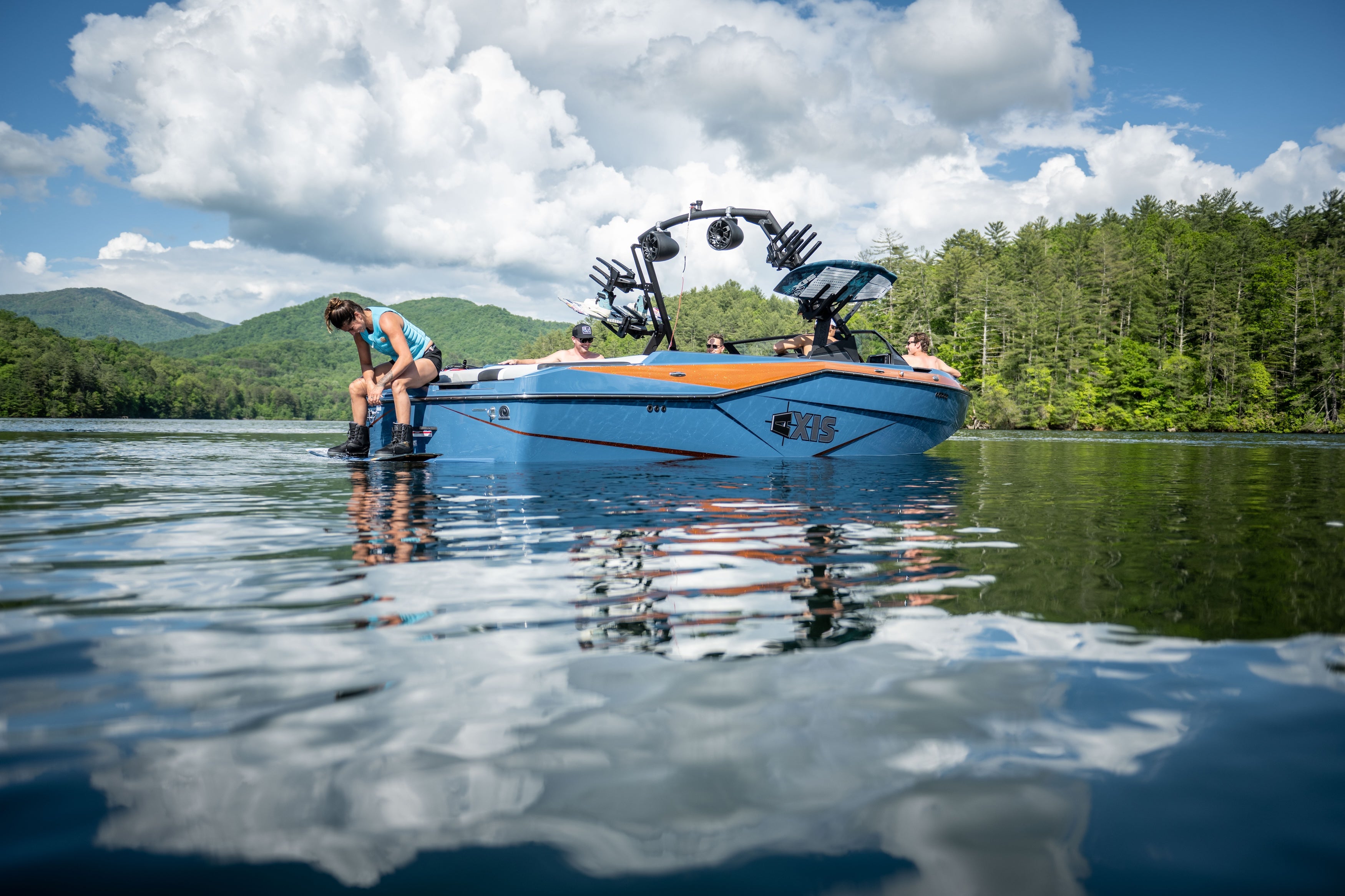 Axis AW20 Black Tower boat on calm waters, showcasing its sleek design and wakeboarding features against a scenic backdrop.