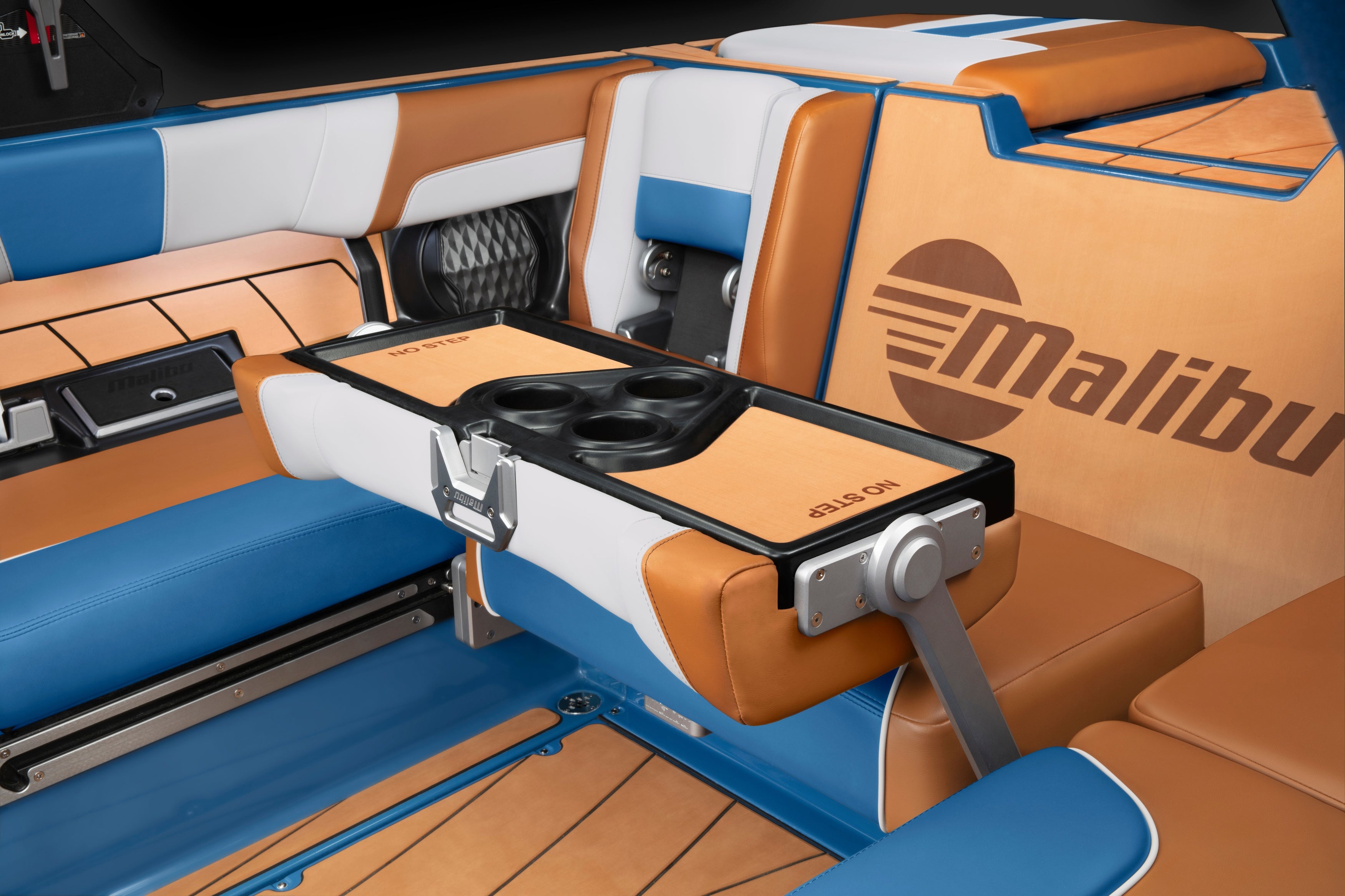 Malibu floor drain with black cup holders, mounted on a boat's colorful, cushioned interior featuring blue, white, and tan upholstery.