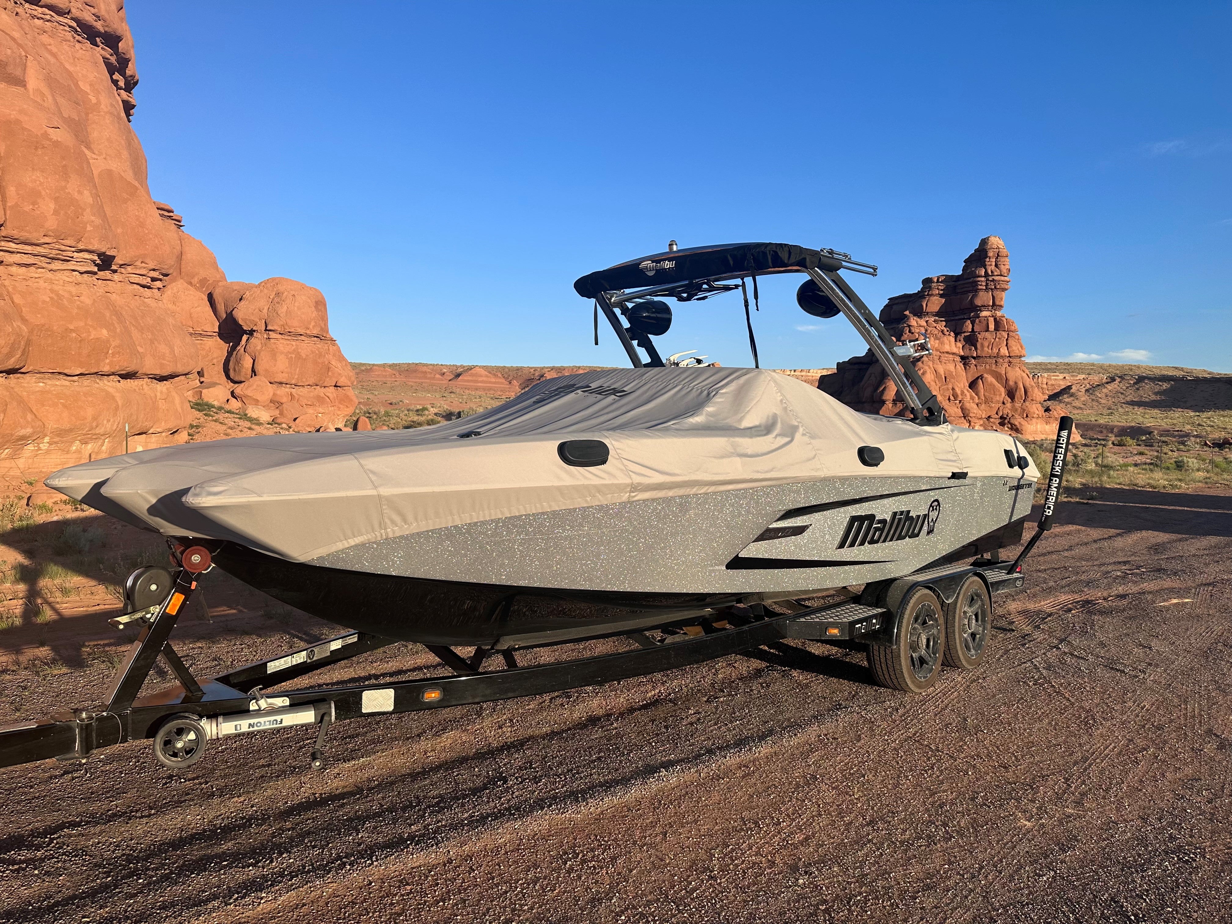 Malibu 24 MXZ Cover for G3 Tower boat, black and beige, on trailer in desert landscape with red rock formations.
