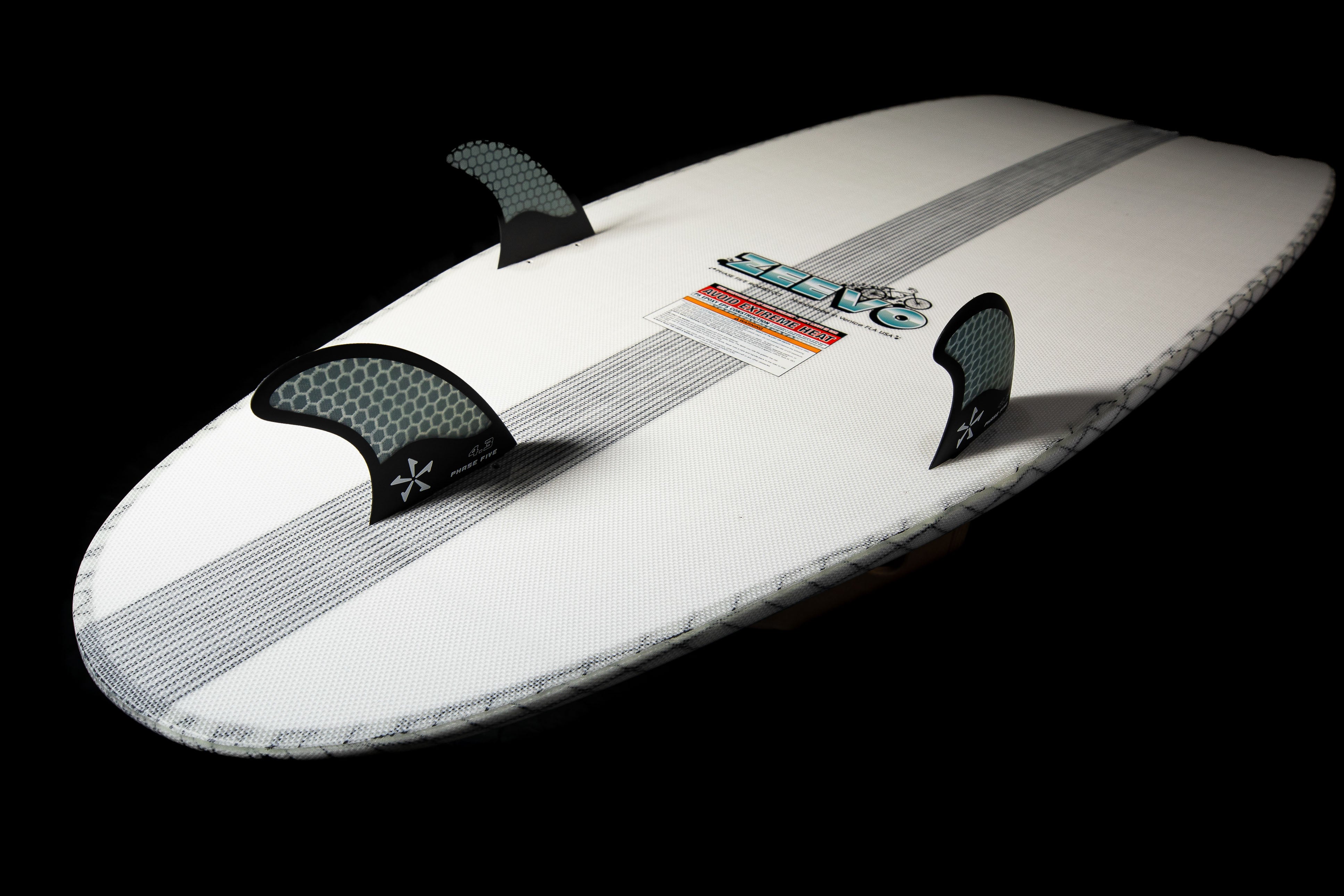 2025 Phase 5 Zeevo surfboard with white deck, black fins, and textured grip pads, designed for advanced surfing performance.