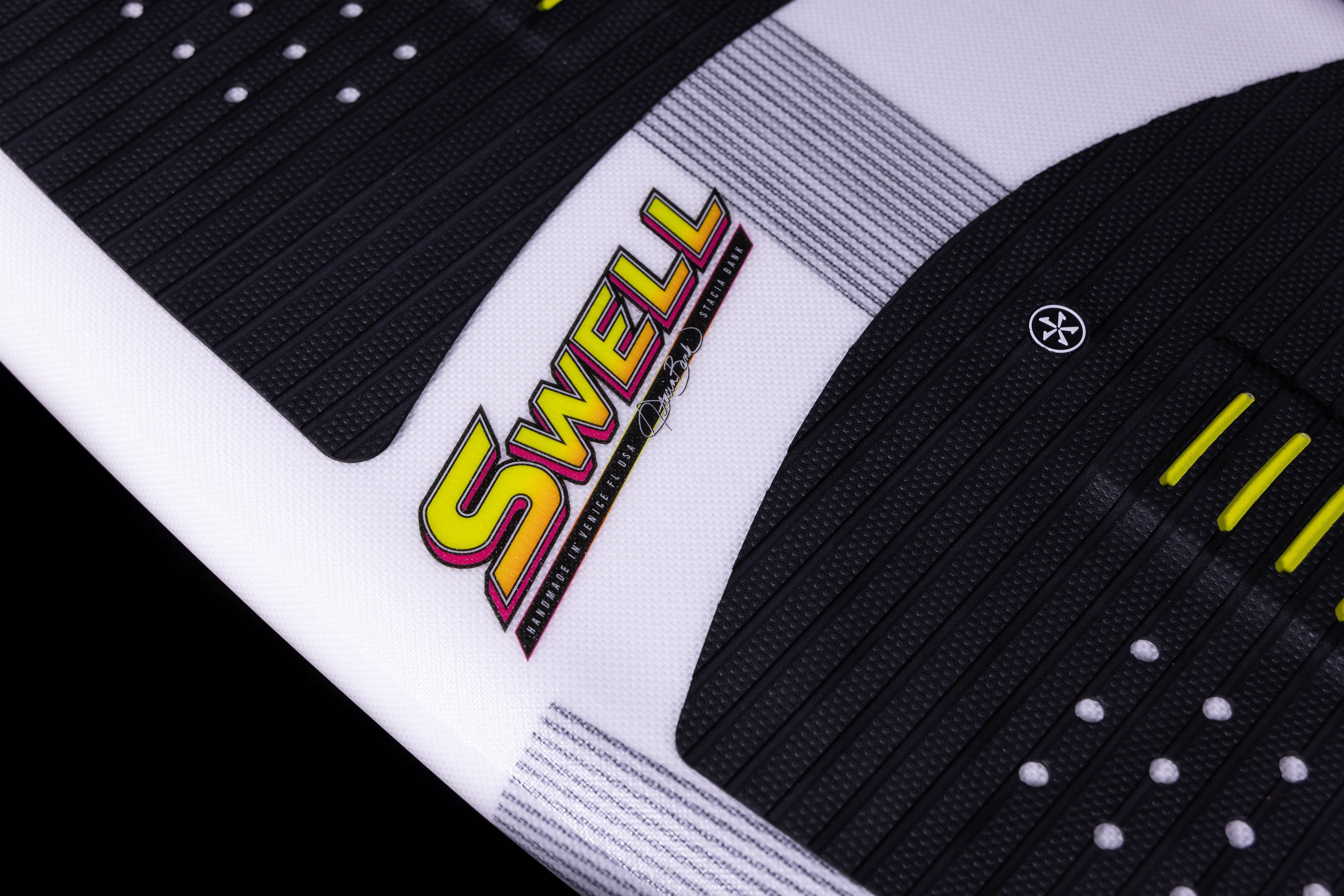 Close-up of the 2025 Phase 5 Swell Surf Board with black traction pads, colorful logo, and textured surface on white background.