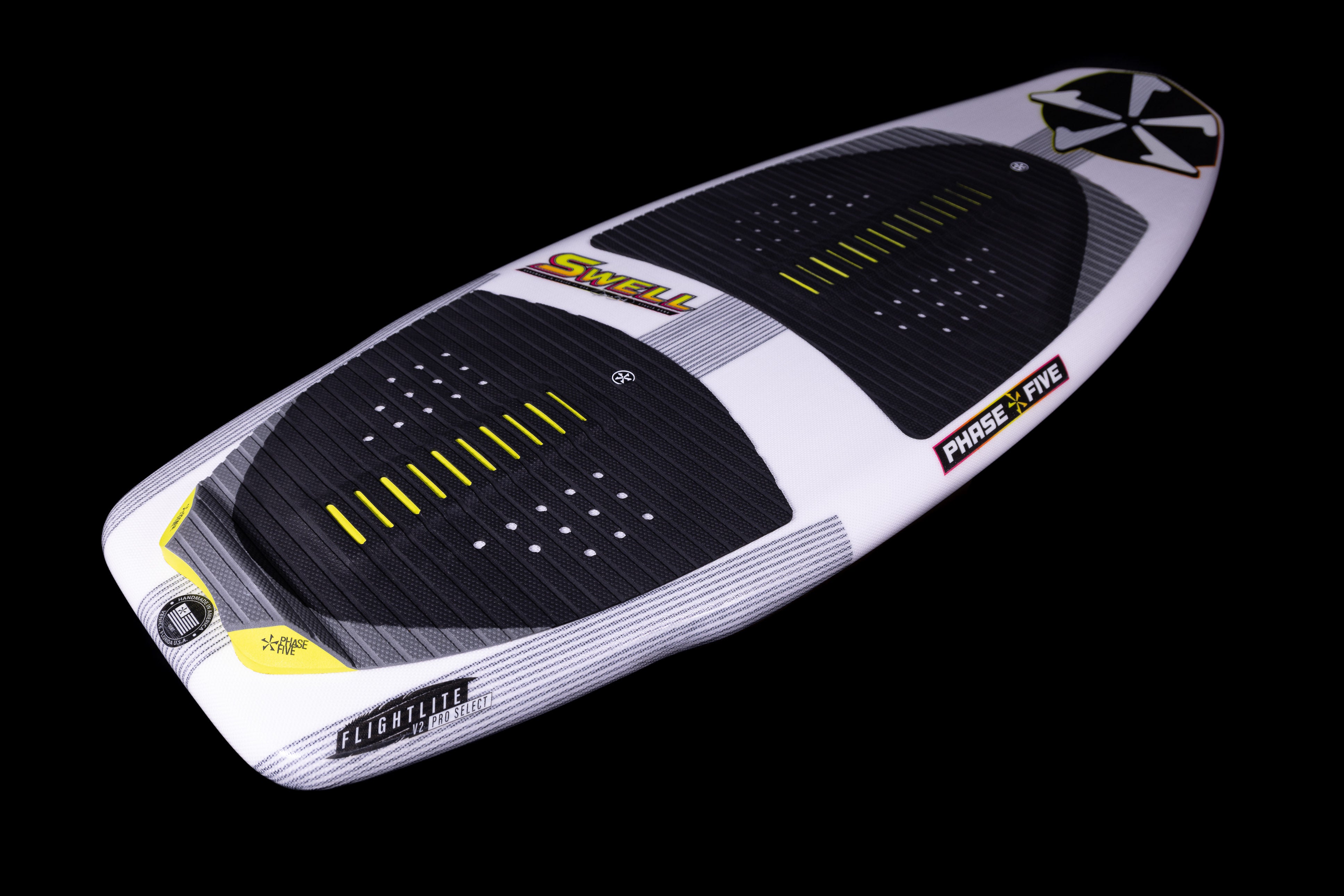 A white and black 2025 Phase 5 Swell surfboard with yellow accents, textured grip pads, and branding details on a black background.