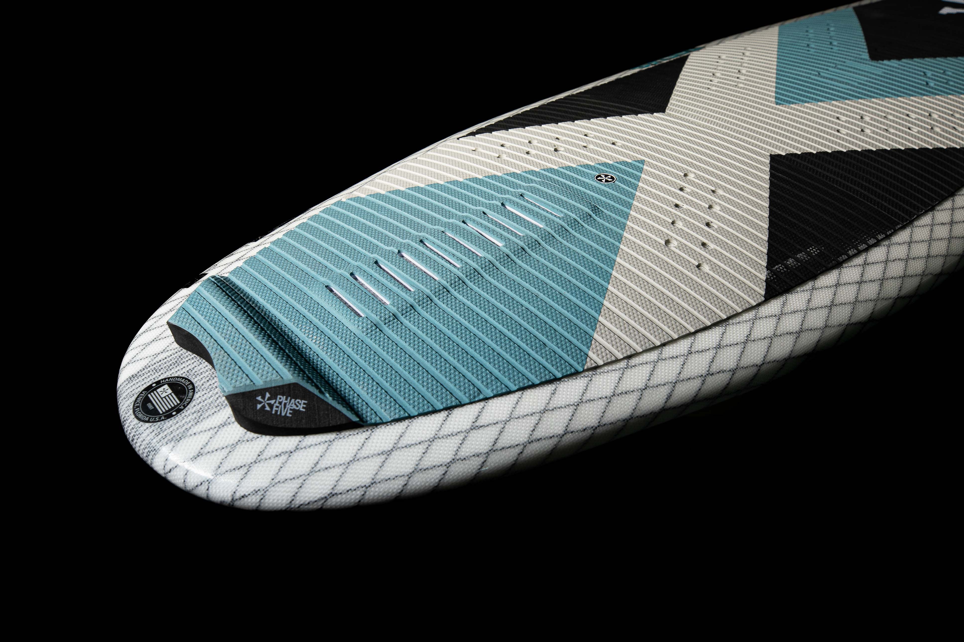 Close-up of the 2025 Phase 5 Zeevo surfboard showing its textured deck, blue traction pad, and sleek design against a black background.