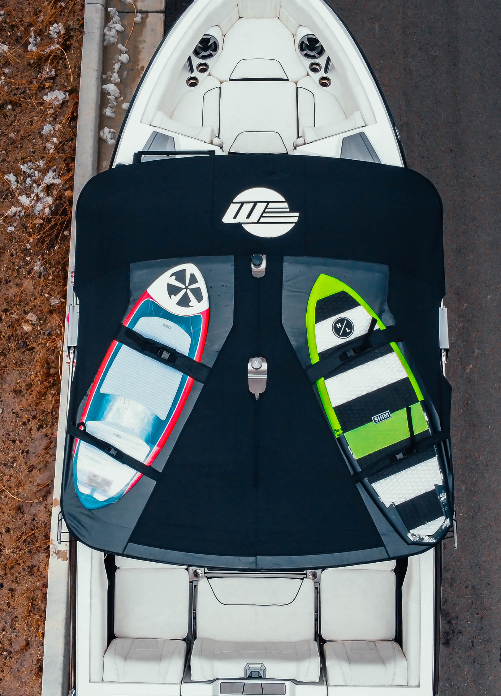 Top view of a Malibu VTX boat with a bimini top and ski tower, holding two wakeboards secured with straps.