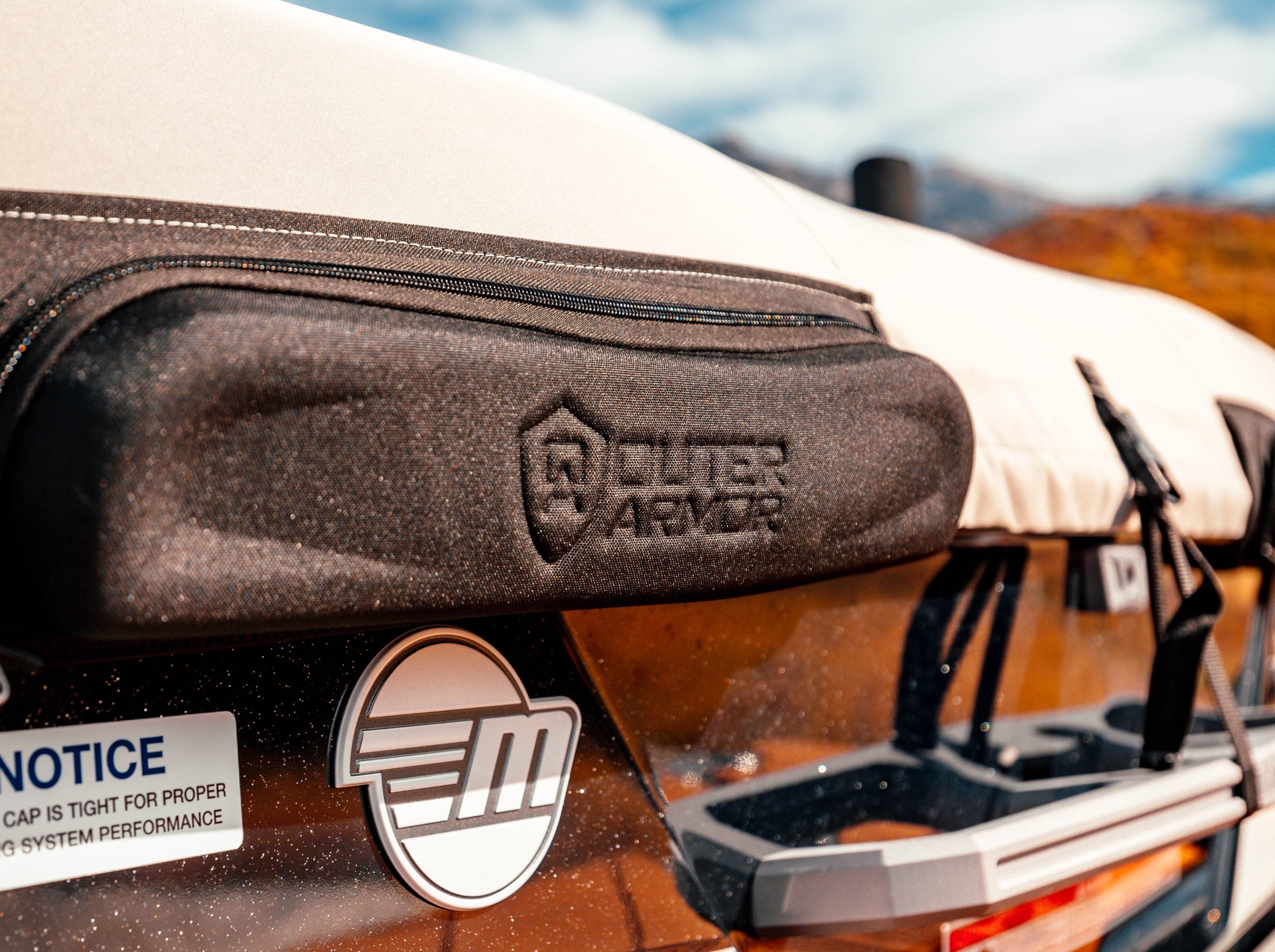 Close-up of a boat cover labeled "23 MXZ Cover - GX Tower Up Position W/Swim Platform Cover & TAPS 3" on a boat with a brown and white exterior.
