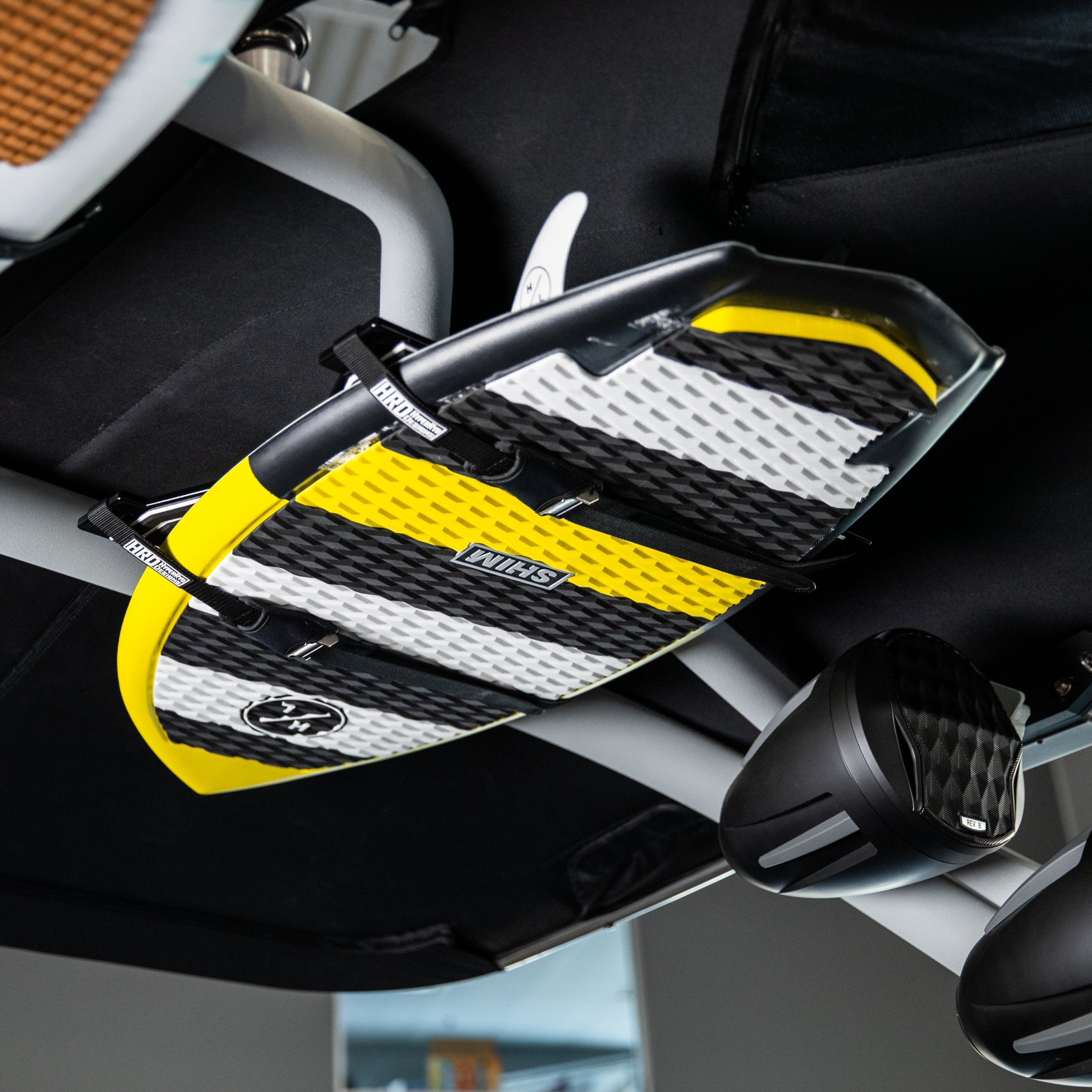 XR1 Surf Rack with GX Towers mounted under a vehicle ceiling, holding a yellow, black, and white surfboard.