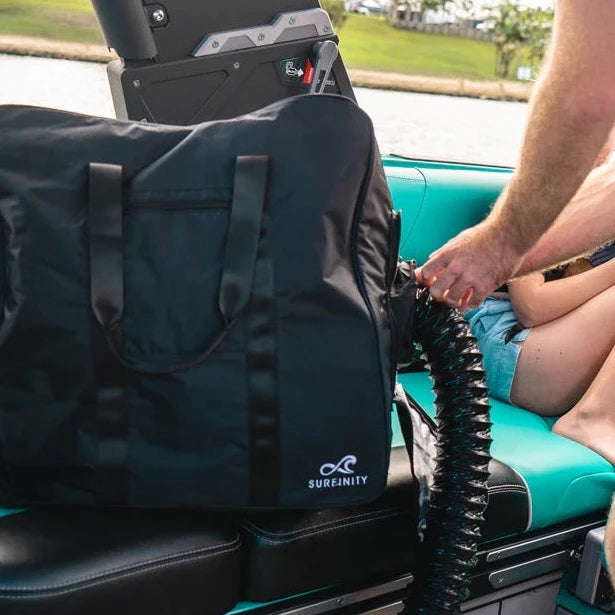 Heated towel bag on a bus seat, connected to a portable heating unit, with a person nearby adjusting the hose.