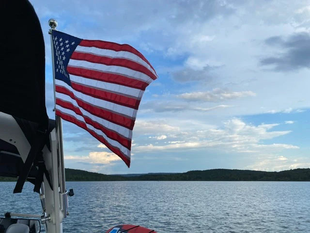 4-foot carbon flag pole with a 3x5 embroidered American flag waving over a scenic lake view.