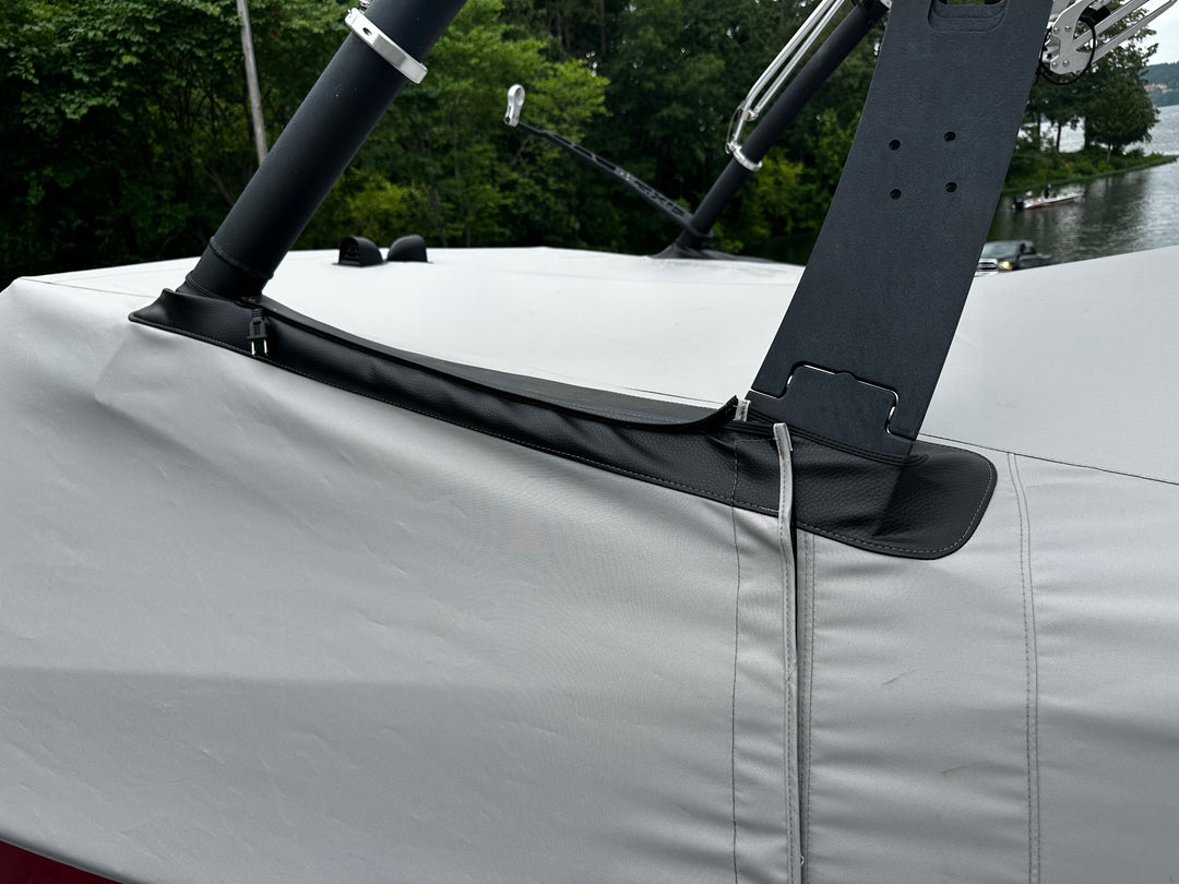 Close-up of a boat cover with a FatAX Tower mount, featuring black leather and metal components, on a boat near a river.