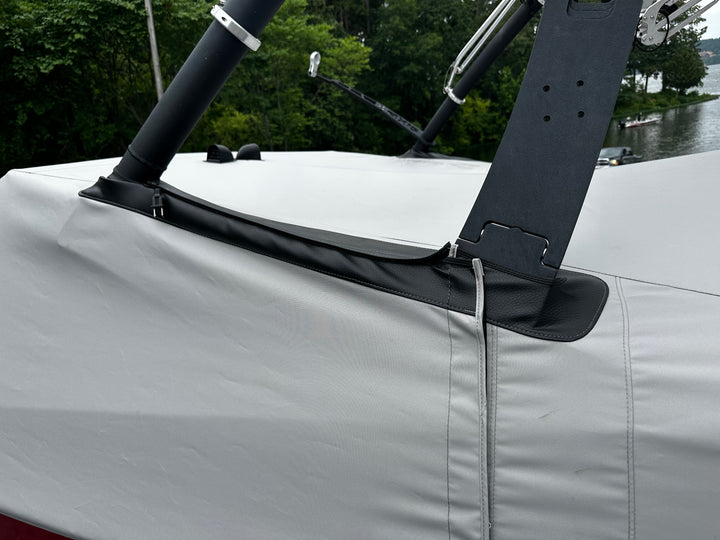 Close-up of a boat cover with a FatAX Tower mount, featuring black leather and metal components, on a boat near a river.