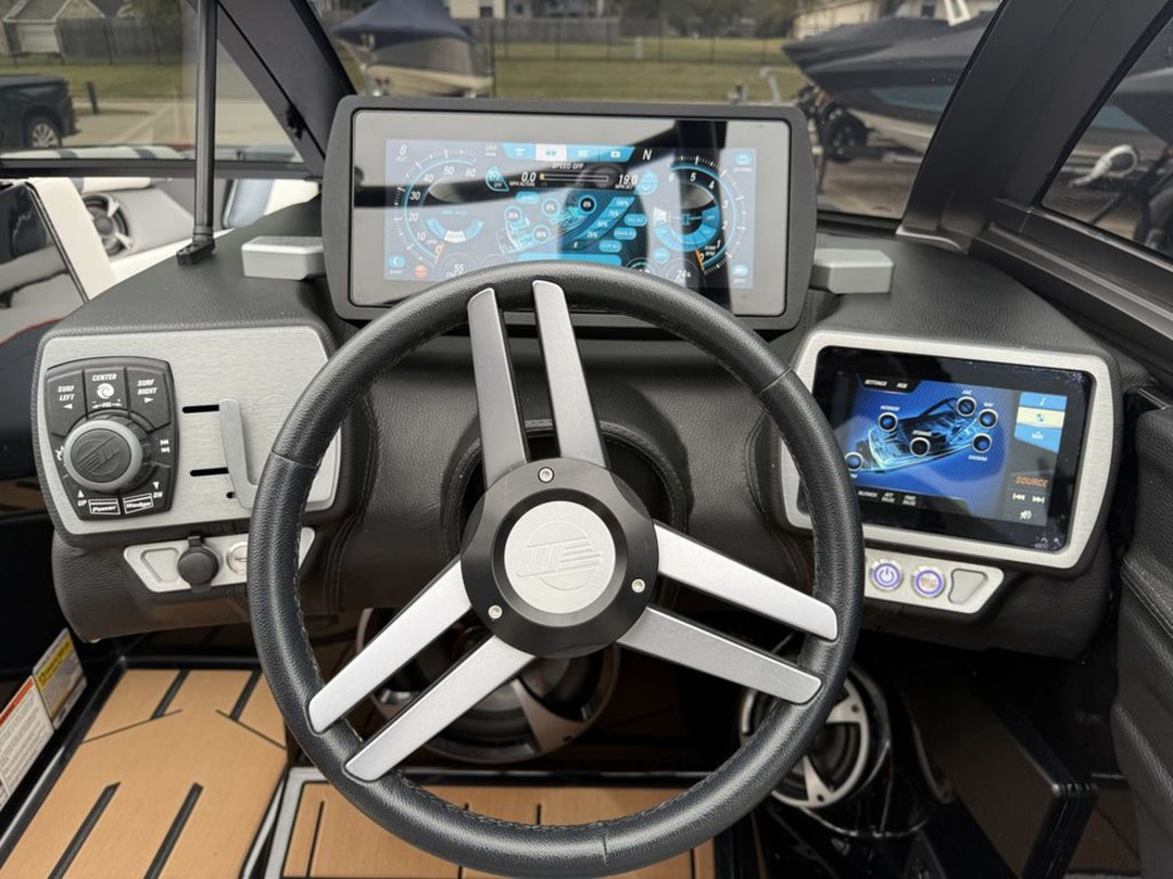 Close-up of a boat dashboard featuring a steering wheel, digital displays, and control panels for navigation and operation.