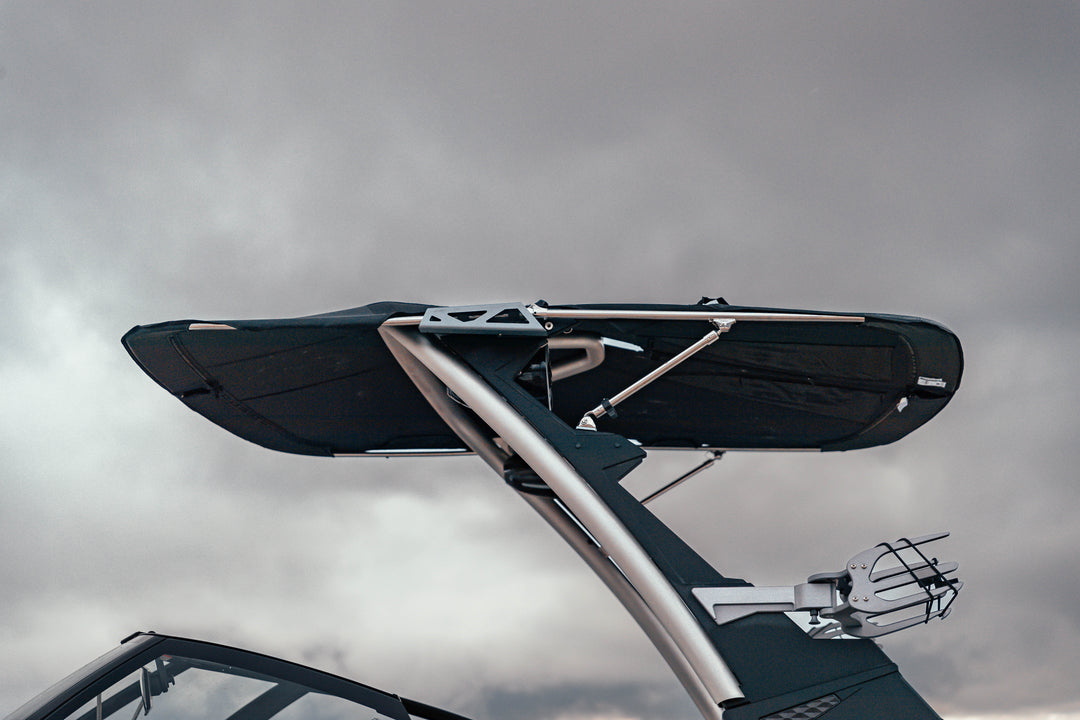 Close-up of Malibu GX Bimini with extension frame mounted on a boat, featuring a black fabric cover and silver support bars.