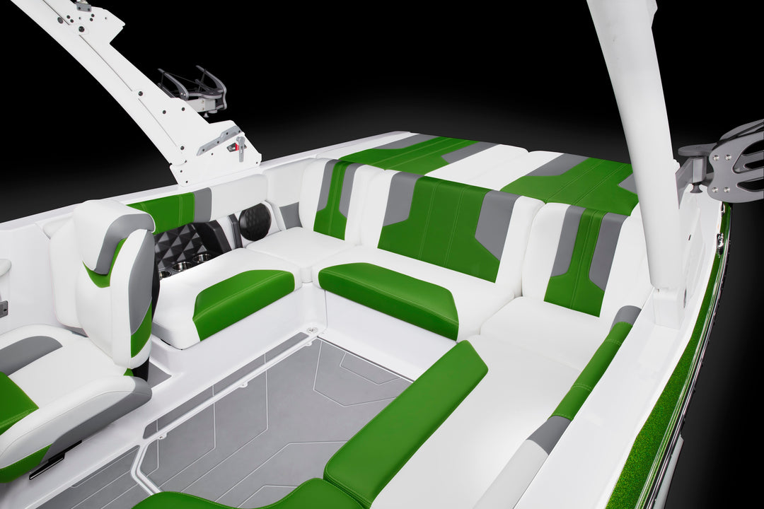 Interior of a boat with white, green, and gray cushioned seating arranged in a U-shape, against a black background.