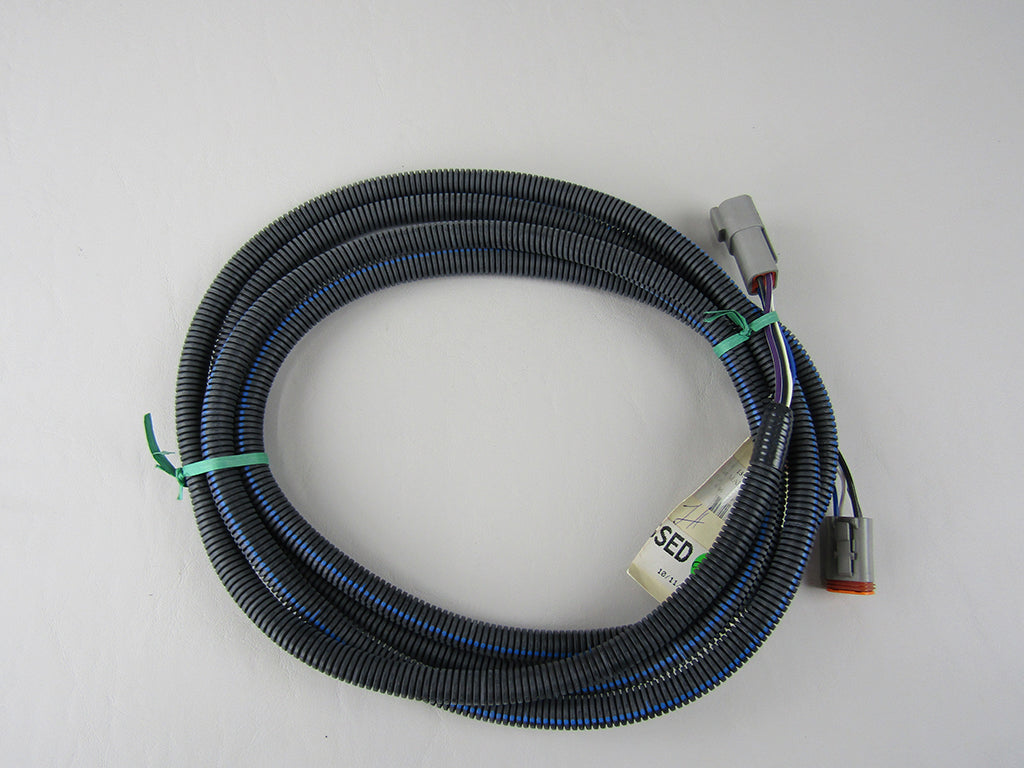 Coiled IO module extension cable with gray connectors and black protective sleeving, used for industrial automation wiring.