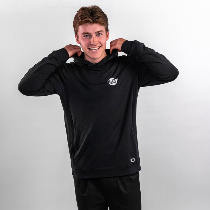 A young man wearing a black Malibu Performance Hoodie, smiling and adjusting the hood, showcasing a sporty style.