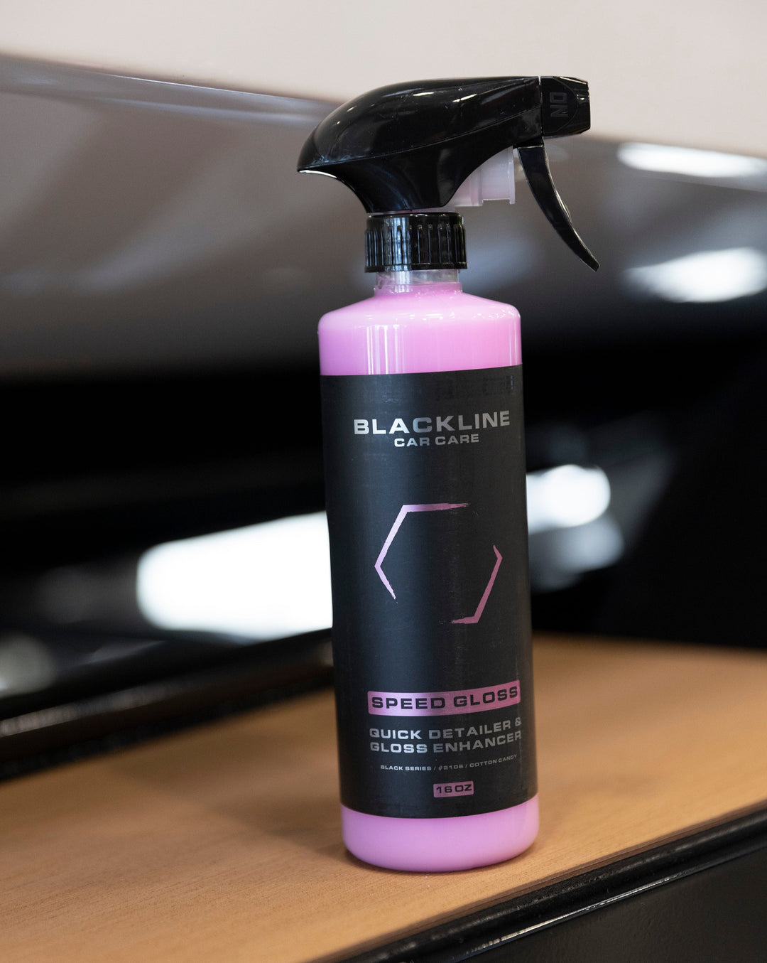 Bottle of Blackline Speed Gloss Quick Detailer and Gloss Enhancer for car care, with black and pink label and spray nozzle.