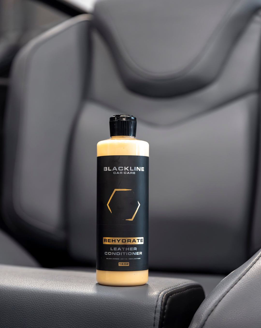 Blackline Rehydrate Leather Conditioner bottle on car seat, designed to nourish and restore leather surfaces.