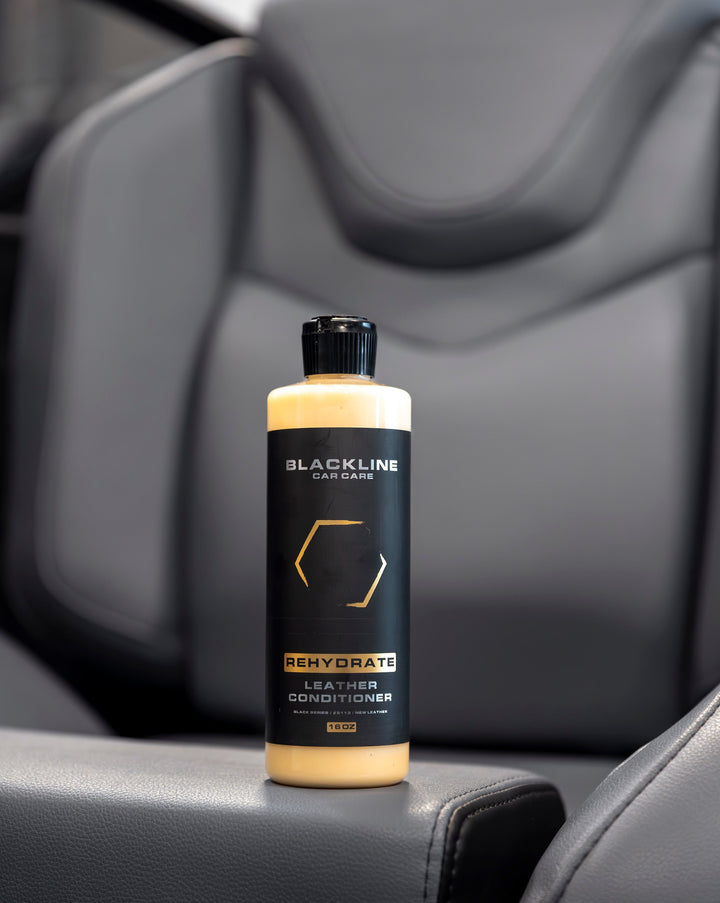 Blackline Rehydrate Leather Conditioner bottle on car seat, designed to nourish and restore leather surfaces.