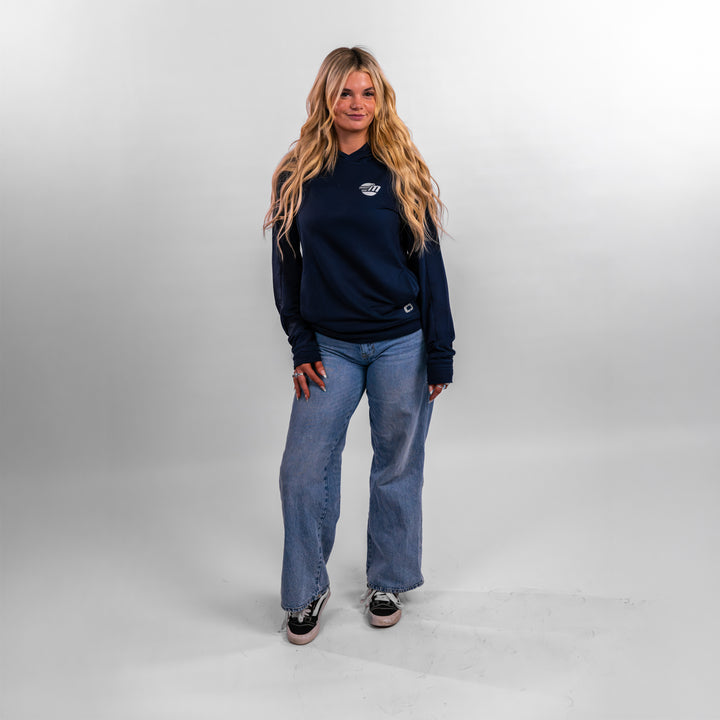 Model wearing a navy Malibu Performance Hoodie paired with light blue jeans, showcasing a casual boating style.
