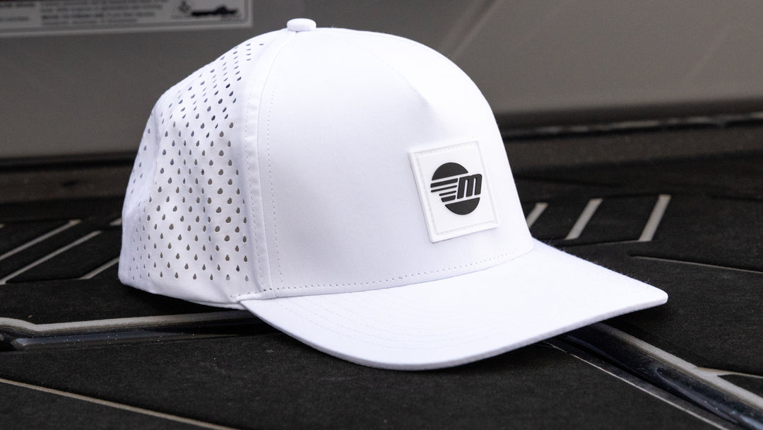 White Malibu Swell hat with perforated sides, a curved brim, and a black and white logo patch on the front.