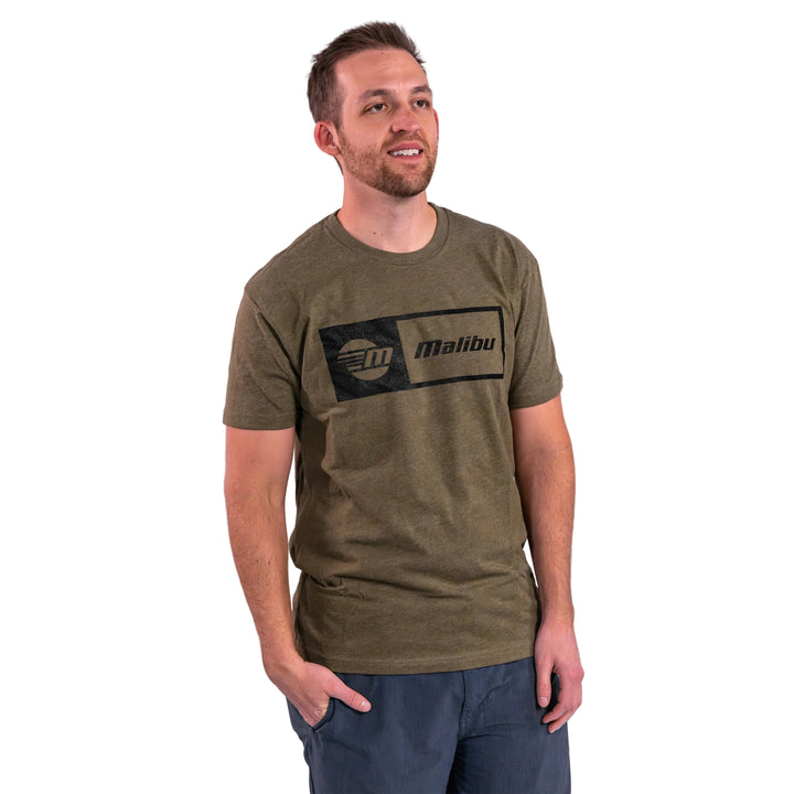 Man wearing a Malibu Statement Tee in olive green, featuring a black logo design, standing against a neutral background.