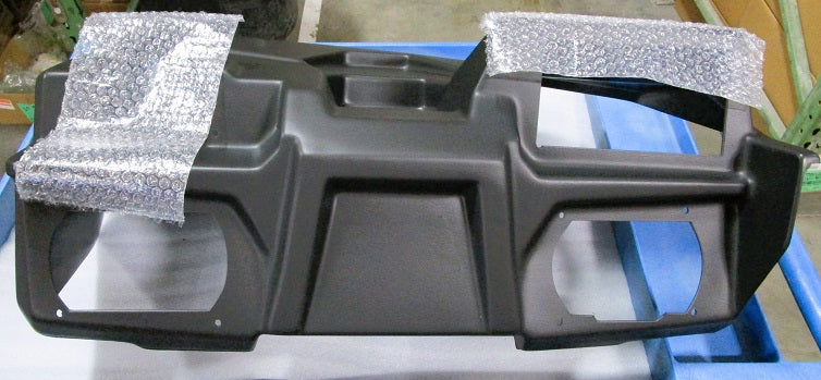 Alt text: "23 Axis Dash Shroud, a black dashboard panel component designed for vehicle customization, partially covered with bubble wrap, displayed on a blue surface in a warehouse setting."