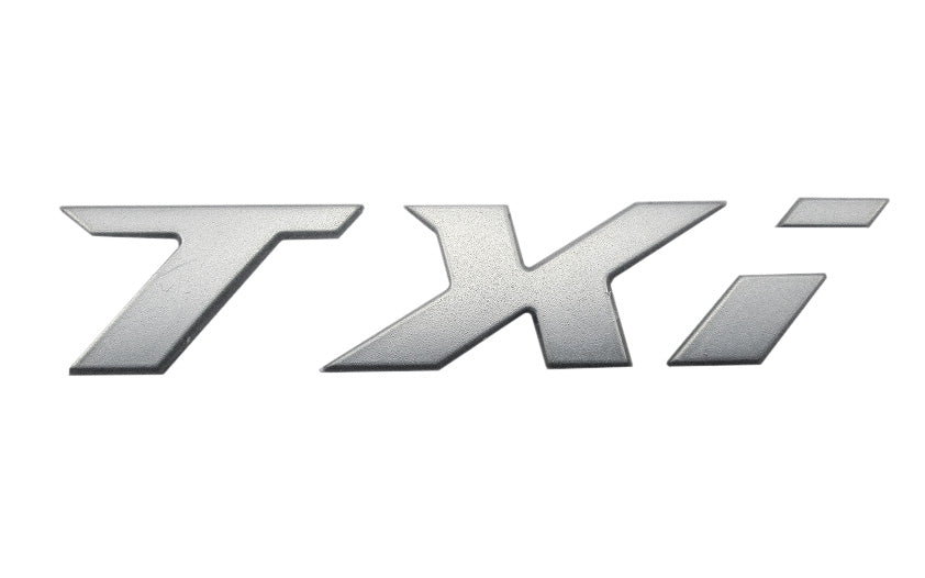 Silver TXi emblem with bold, stylized lettering, designed for vehicle branding or customization.