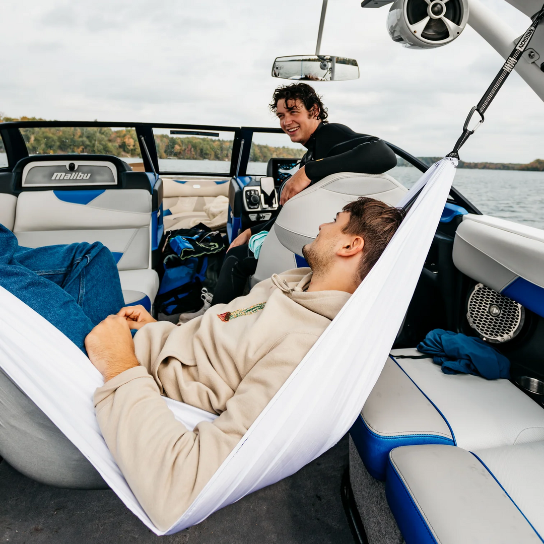 Two men relax on a Mission Boat hammock inside a boat, enjoying the water view and comfortable lounging on the watercraft.