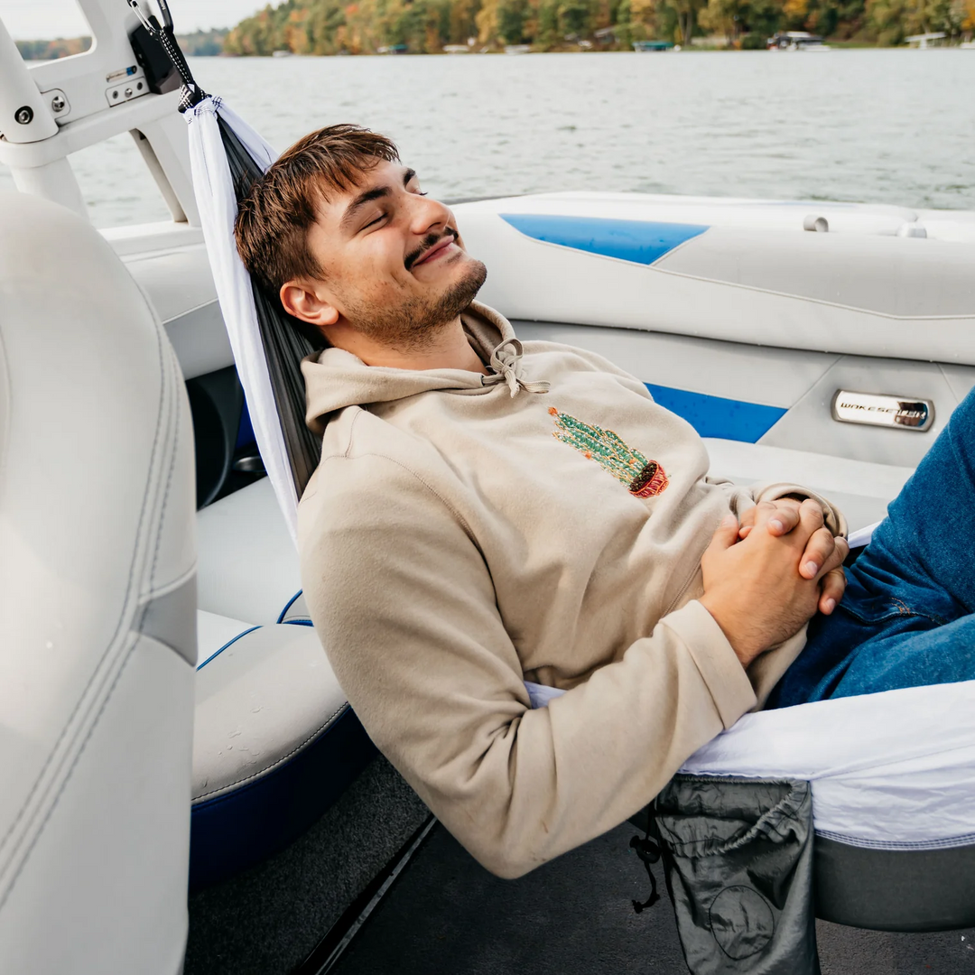 Man relaxing in a Mission Boat hammock on a boat, enjoying the water and nature with a peaceful expression.