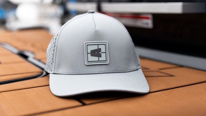 Gray Axis Swell Hat with a square logo featuring a black number 4 on the front, placed on a wooden surface.