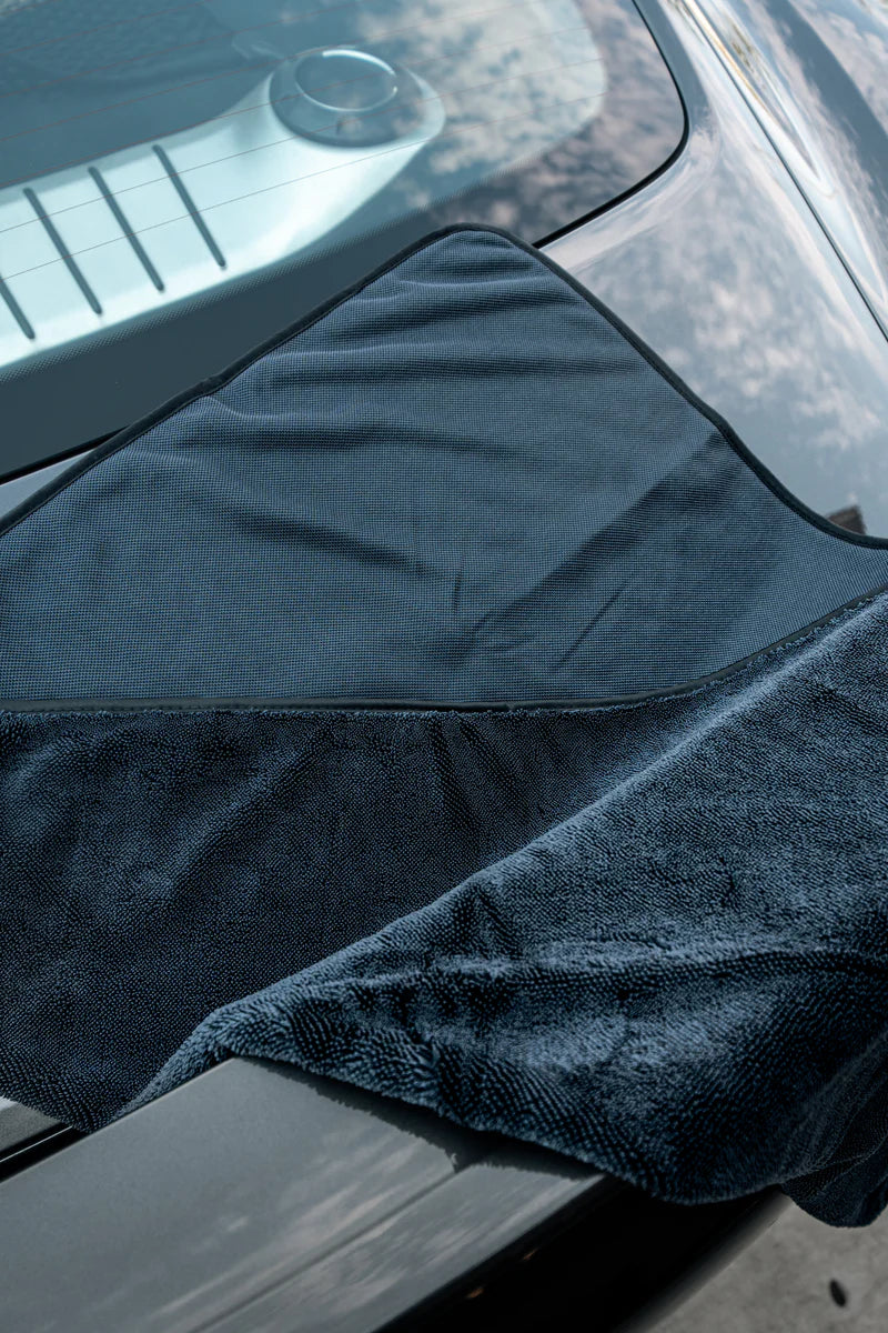 Slim twisted-loop drying towel draped over a car hood, showcasing its absorbent texture and sleek design for effective drying.