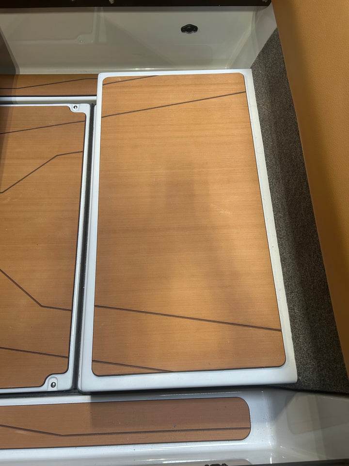 Close-up of an axis transmission cover with a wooden finish, framed in white, installed on a boat or vehicle interior.