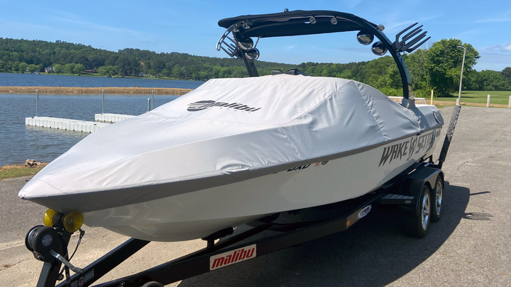 Cover for Sunscape/Wakesetter 247 boat with Illusion X/XS Tower, 63" height, on a trailer near a lake.