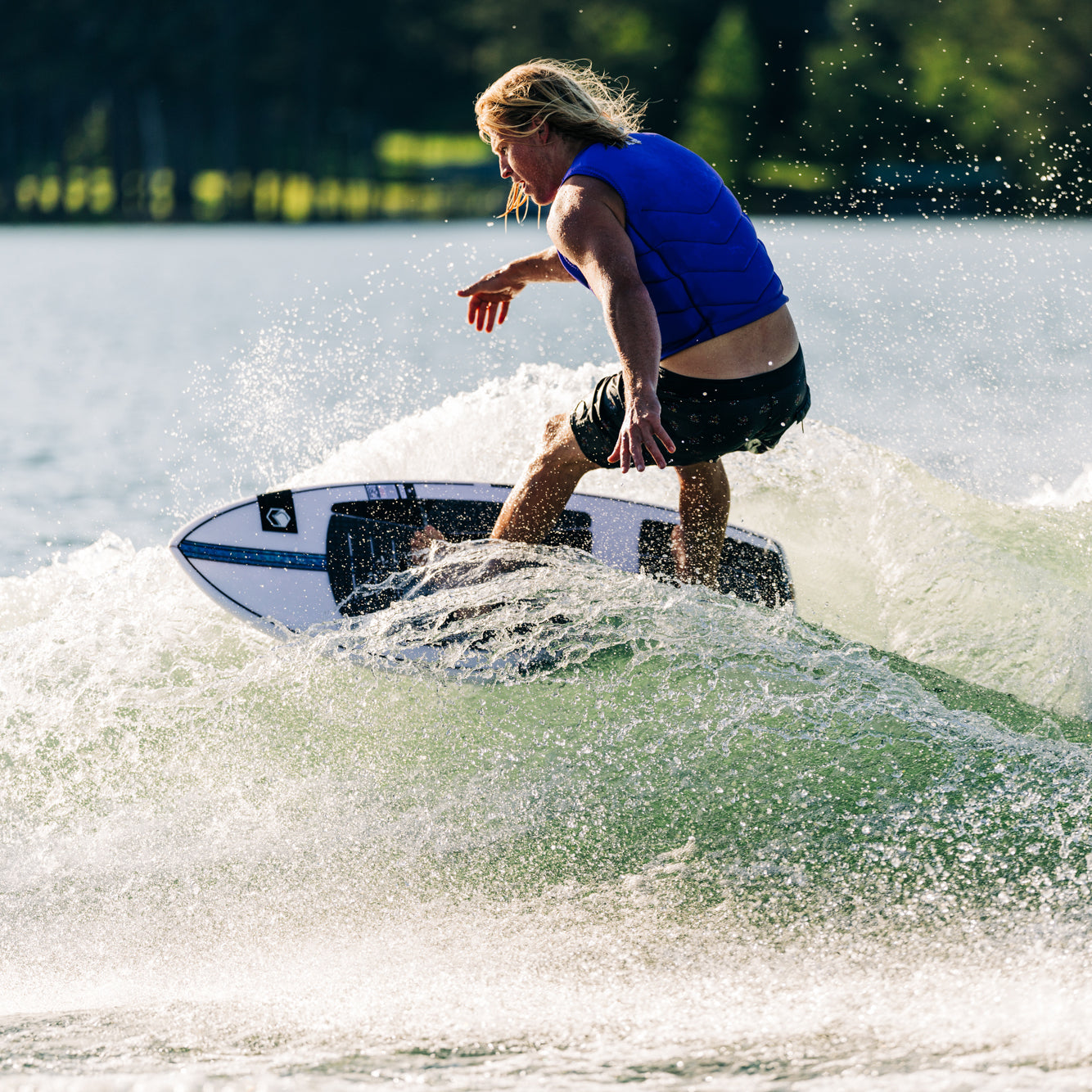 A person in a blue life vest rides the 2025 Liquid Force Flyer wakesurf board on a wave.