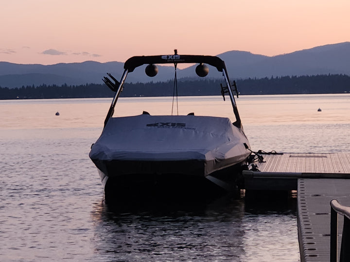 Axis A245 cover for AW20 tower and swim platform, protecting the boat at sunset by the dock. Ideal for outdoor storage.