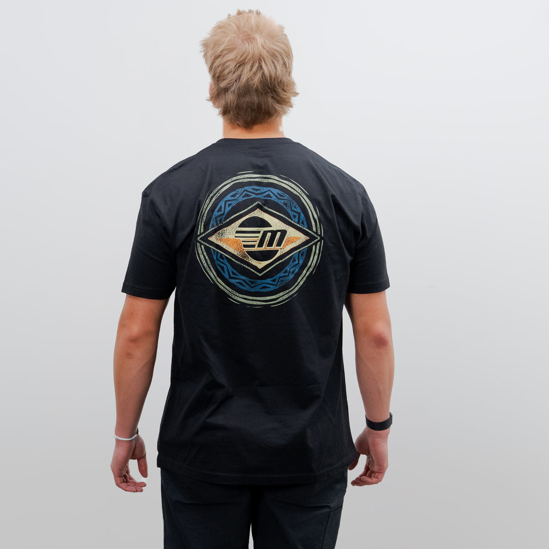 Back view of a person wearing a black Malibu Surfer Tee with a colorful, circular surf-inspired graphic on the back.