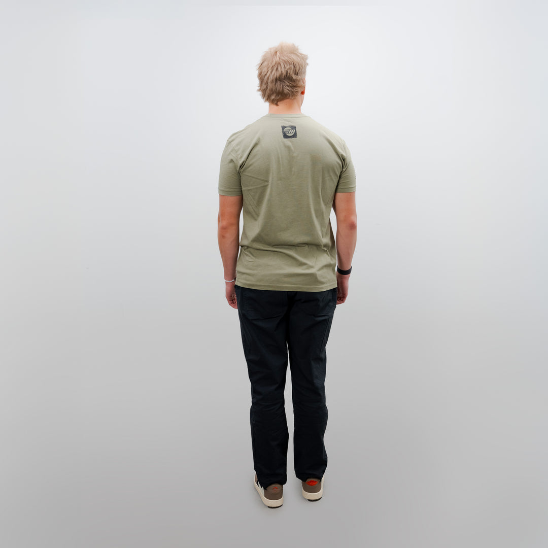 Back view of a person wearing a light green Malibu Freedom Tee 2.0 with a small logo on the upper back, paired with black pants and sneakers.