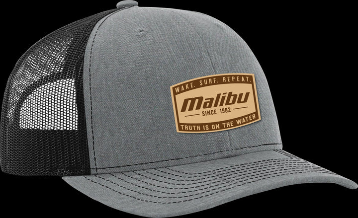Gray trucker hat with a brown Malibu patch featuring the slogan "Wake. Surf. Repeat." and "Truth is on the water" on a black background.